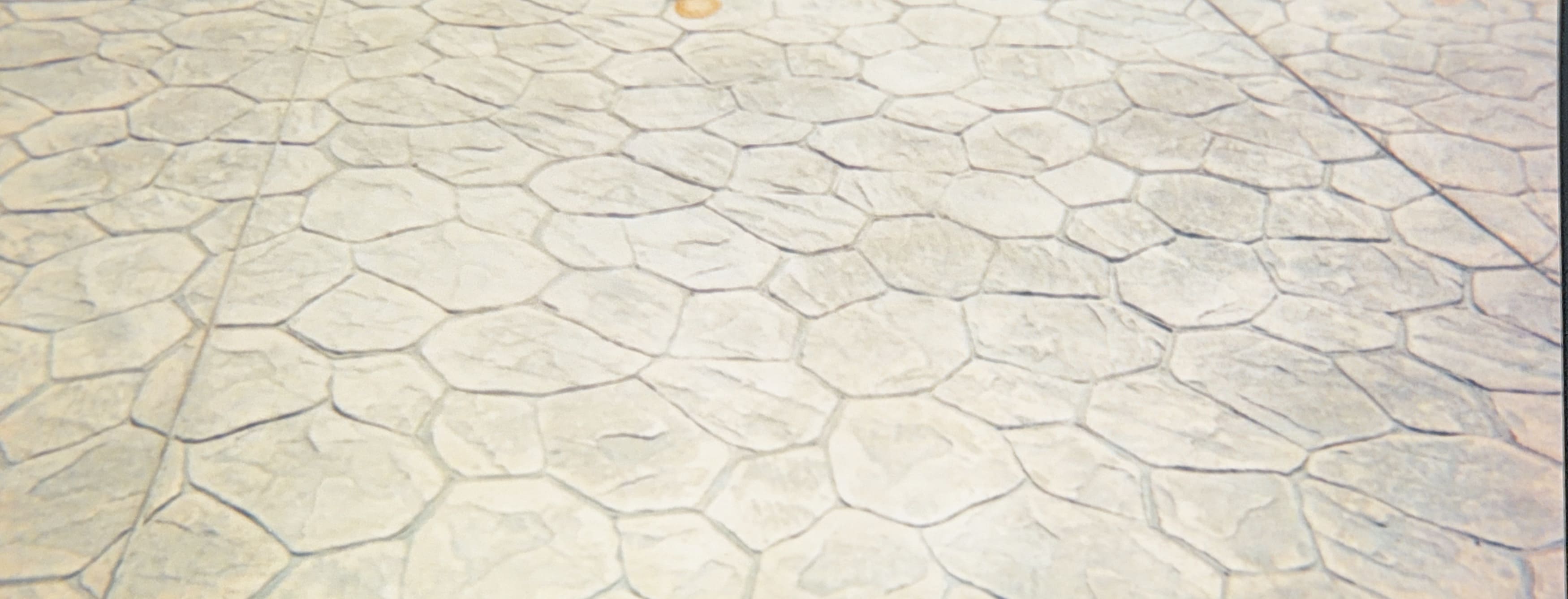 Close-up of light-colored stamped concrete with an irregular flagstone pattern