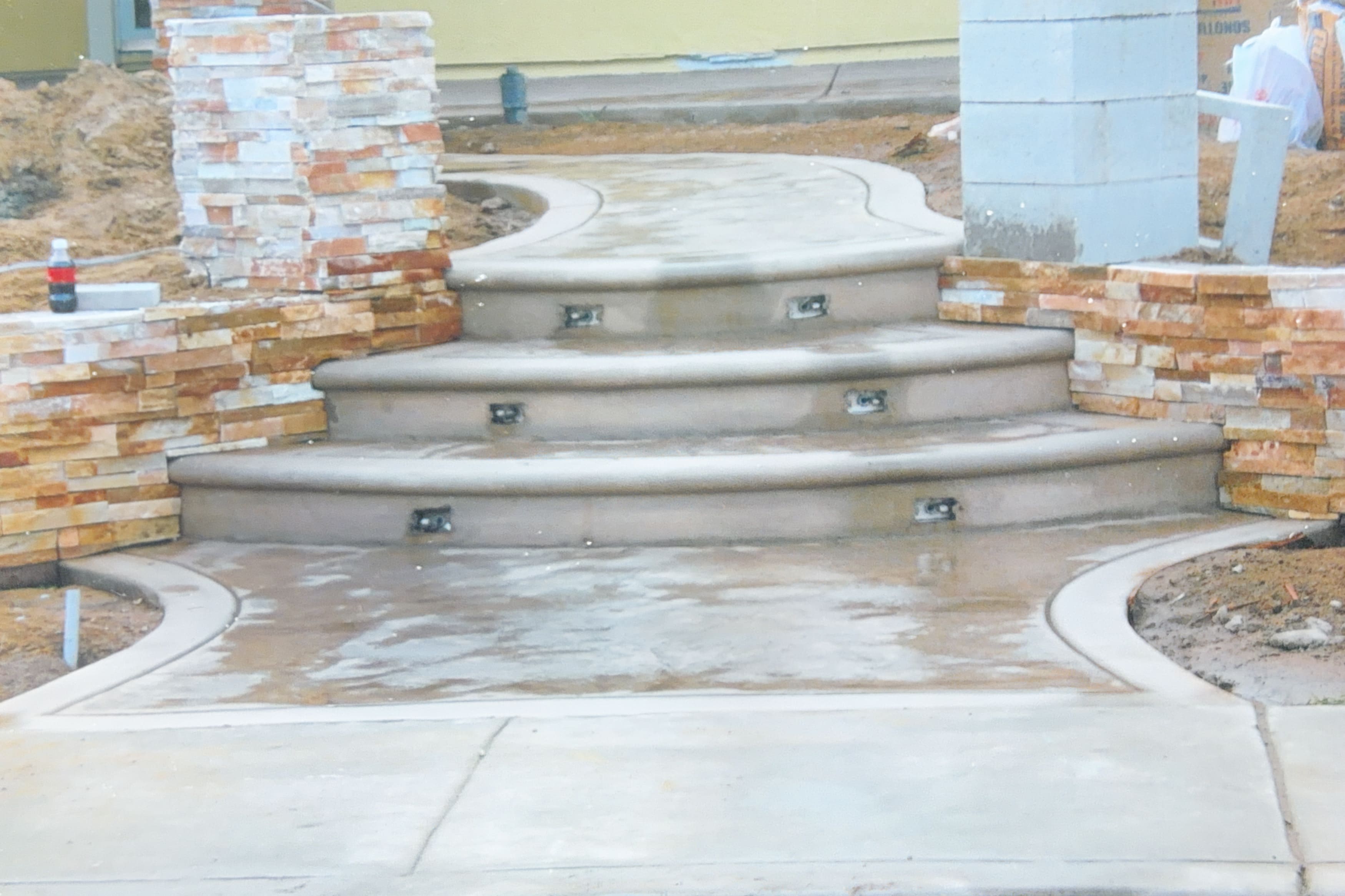 Concrete steps under construction with integrated lighting and stone veneer retaining walls