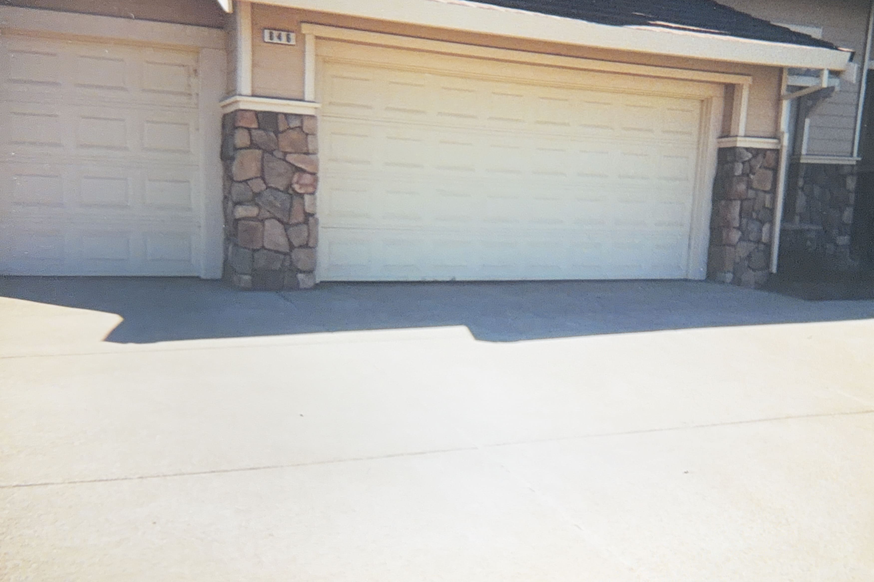 A house exterior showing a garage door and stone veneer columns with a concrete driveway
