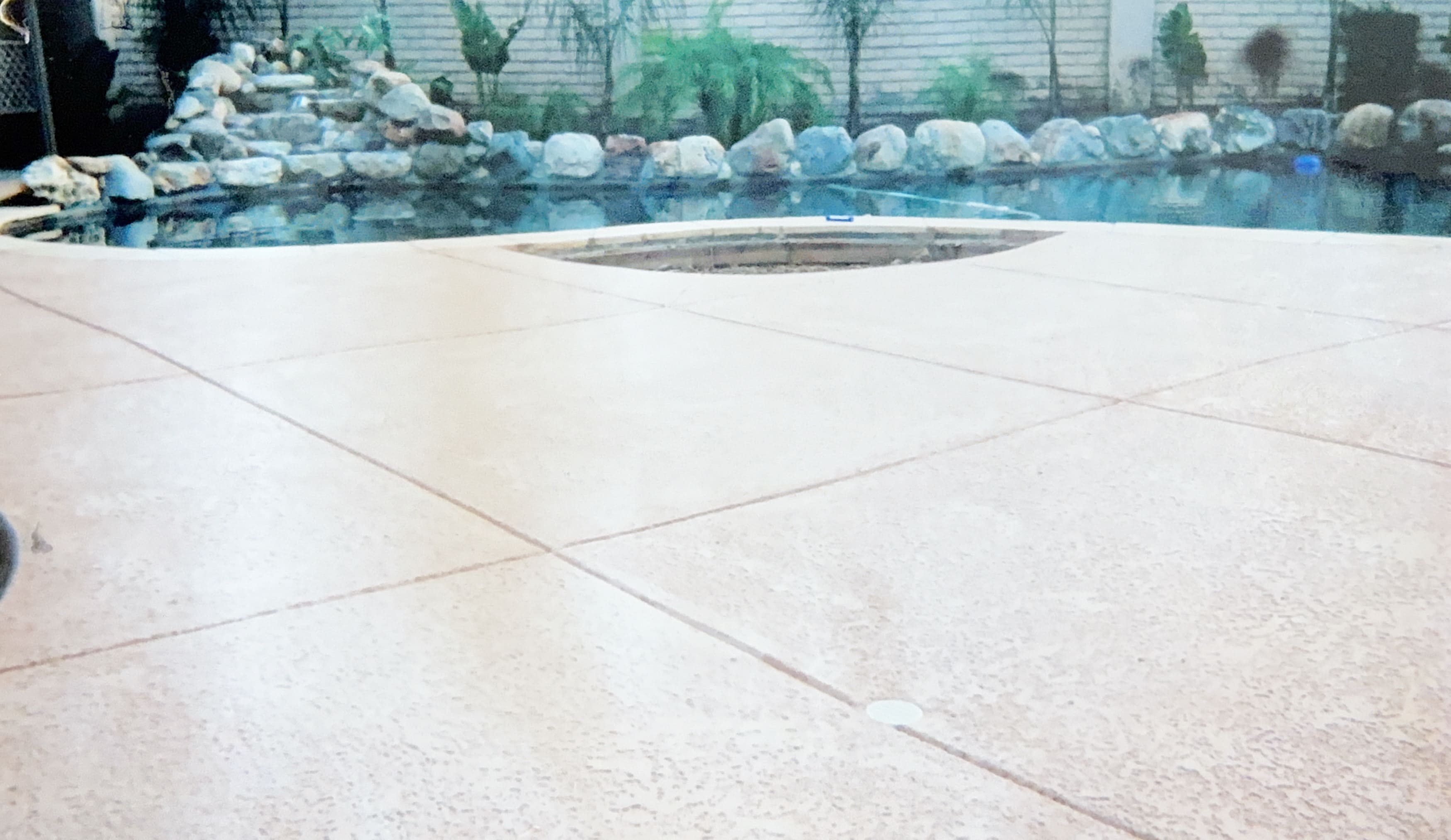 Custom pool area with rock waterfall and expansive concrete decking