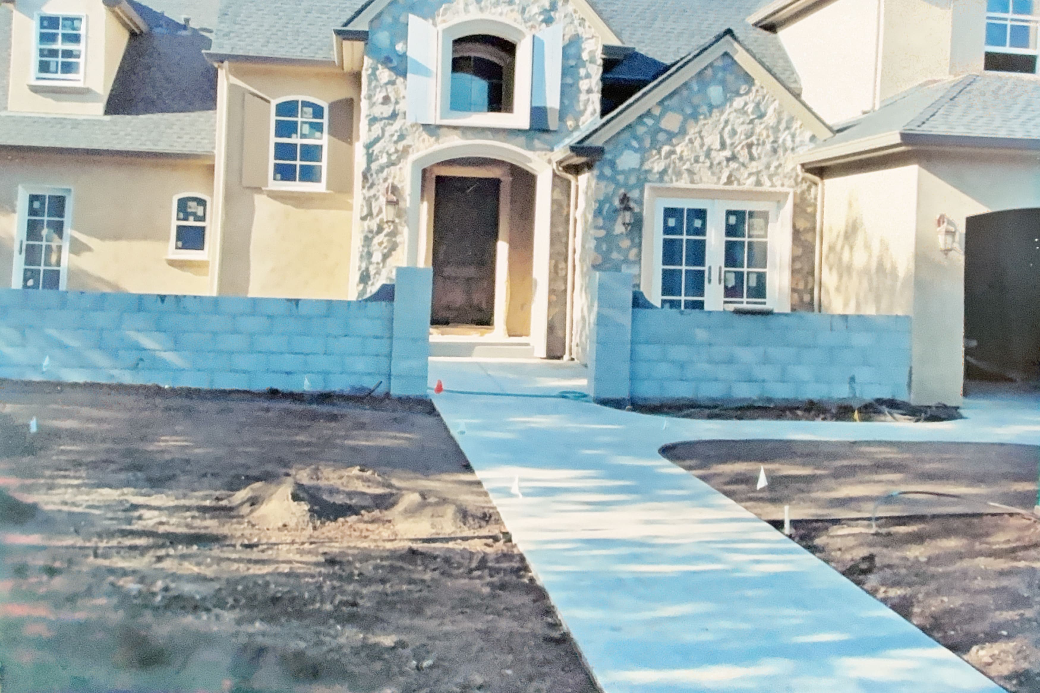 Front entrance of a house with a freshly poured concrete walkway and low cinder block walls