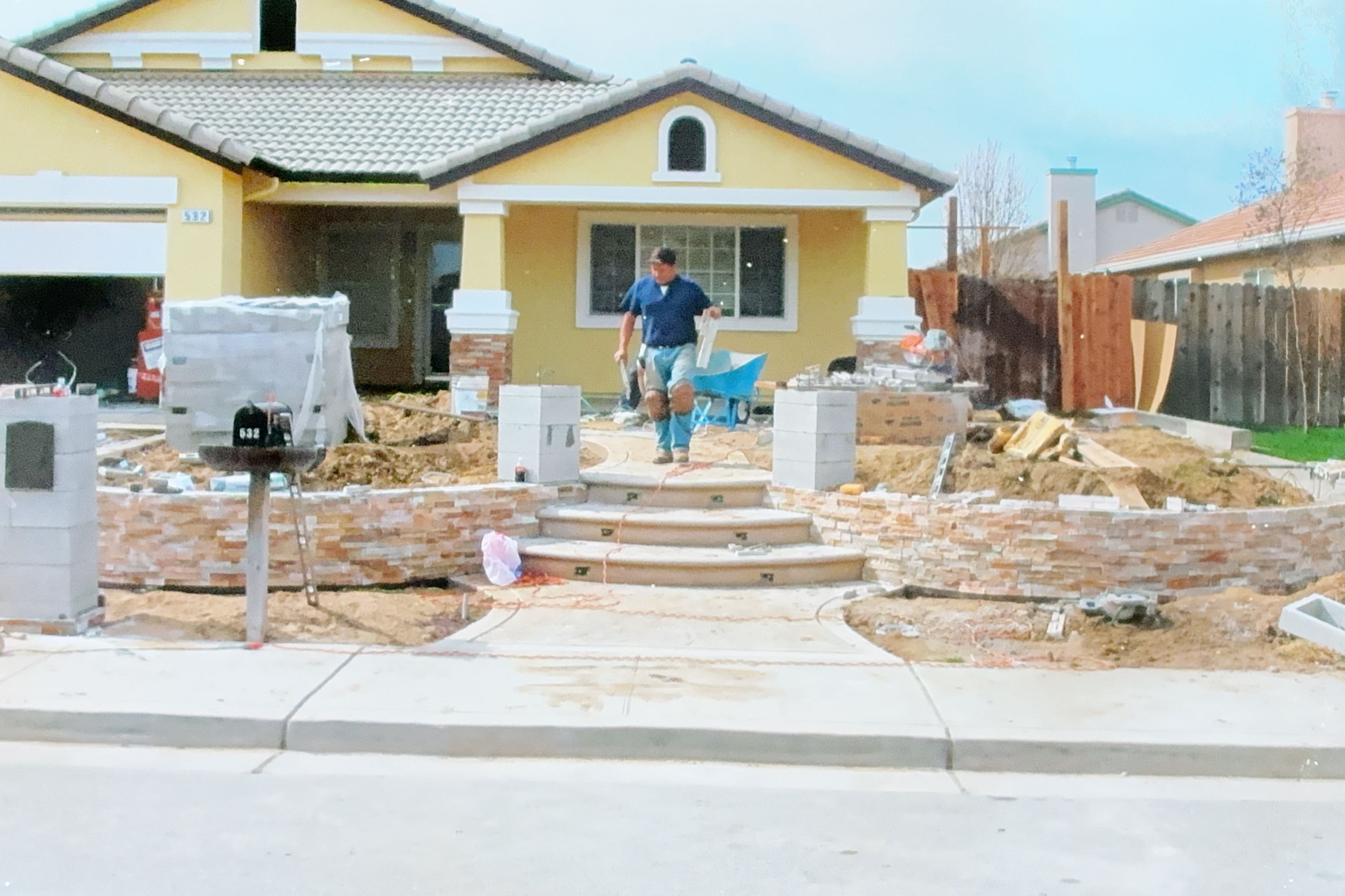 Worker constructing stone veneer retaining walls for a front yard