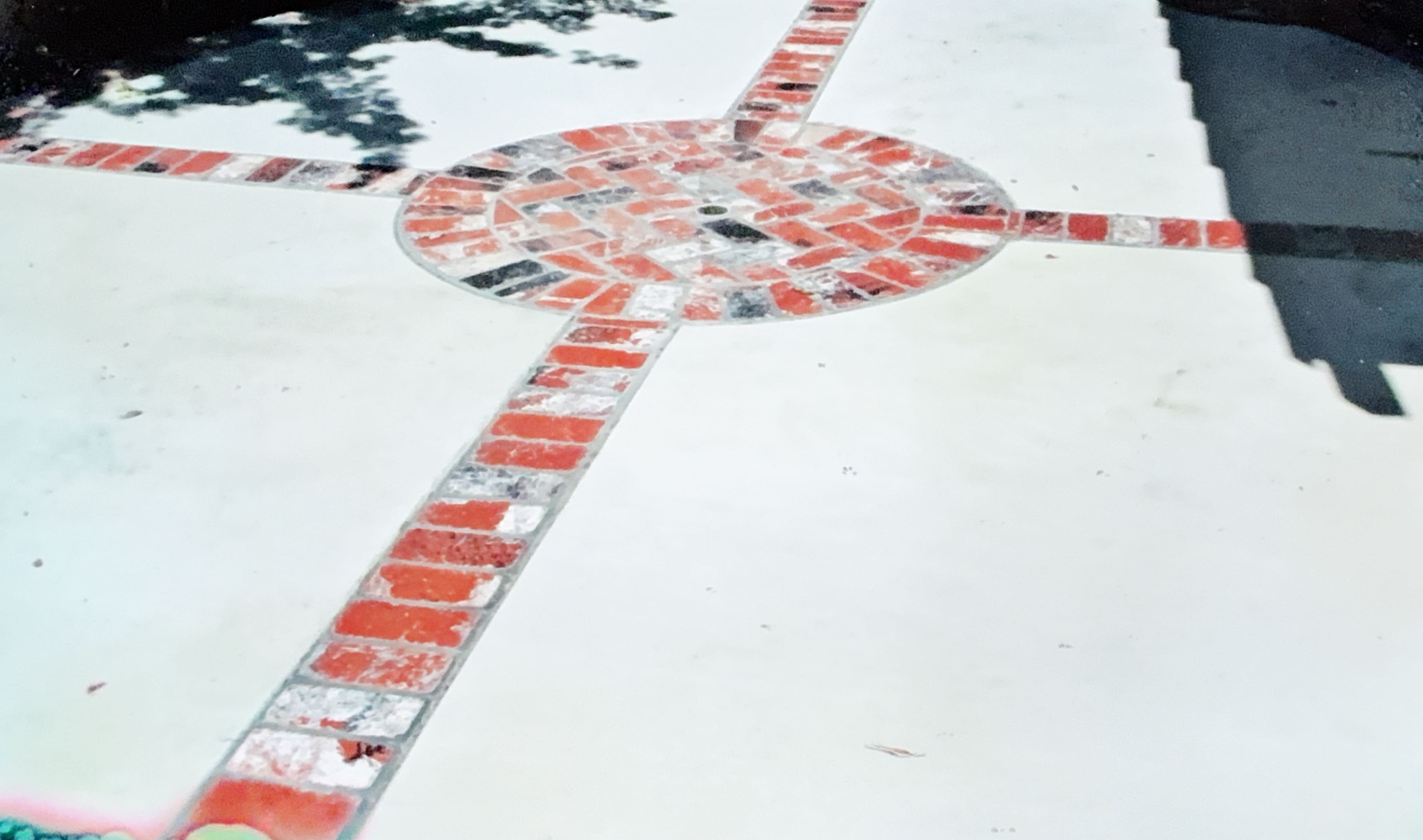 Decorative concrete flatwork featuring red brick inlays in a cross and circle pattern