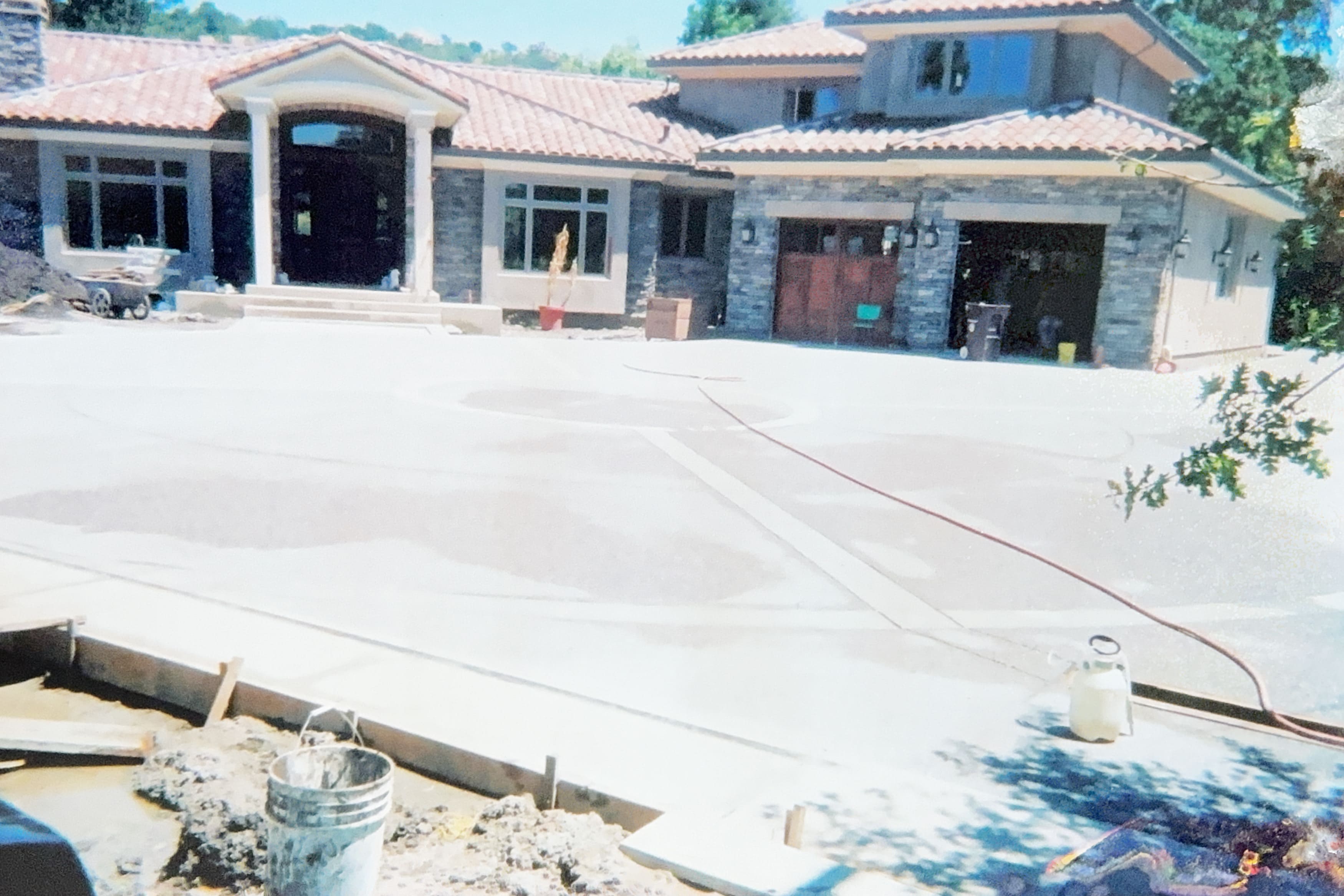 Large freshly poured concrete driveway in front of a house with stone veneer accents