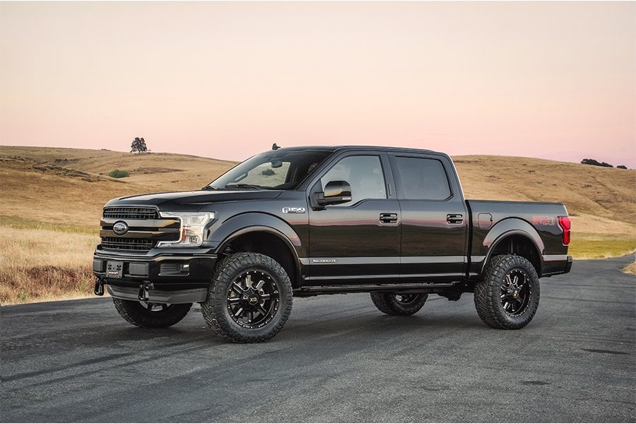 Black Ford F-150 with a level stance on custom wheels at sunset