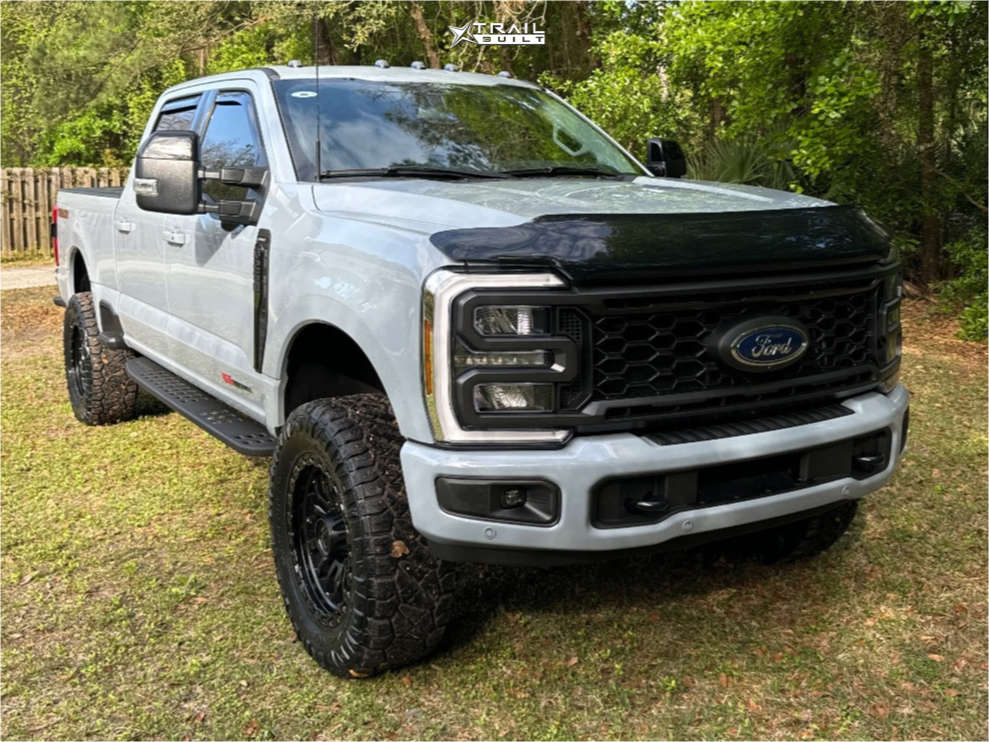 Leveled white Ford Super Duty with black wheels and all-terrain tires