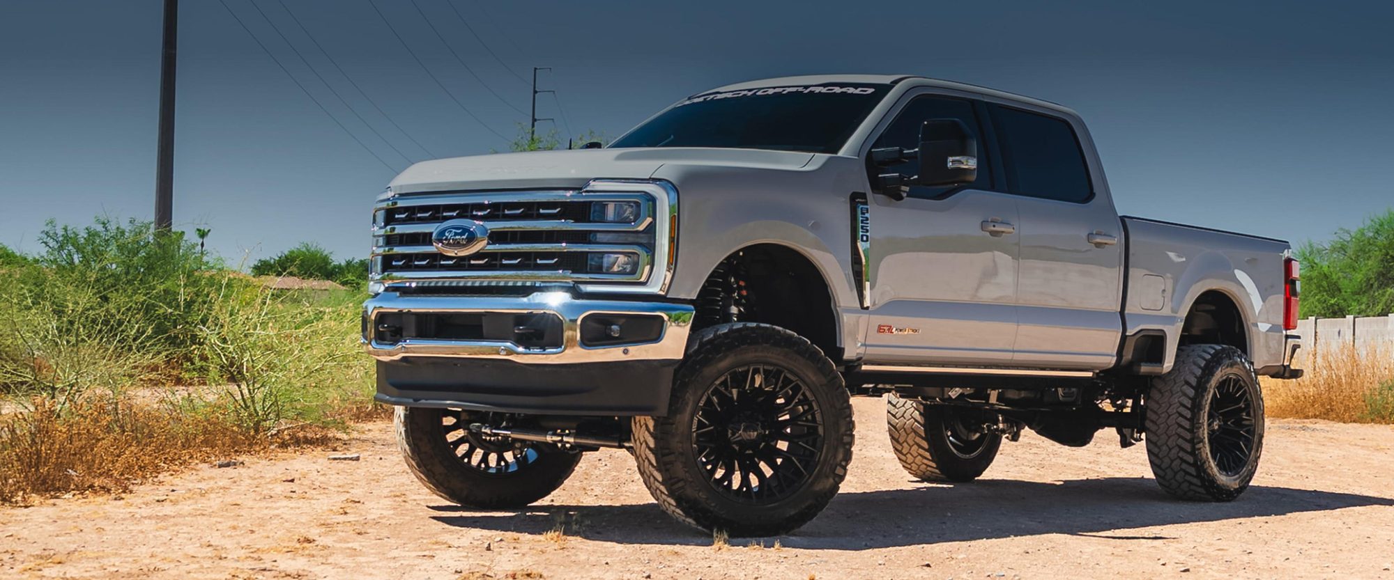 Silver Ford Super Duty on black aftermarket wheels and all-terrain tires