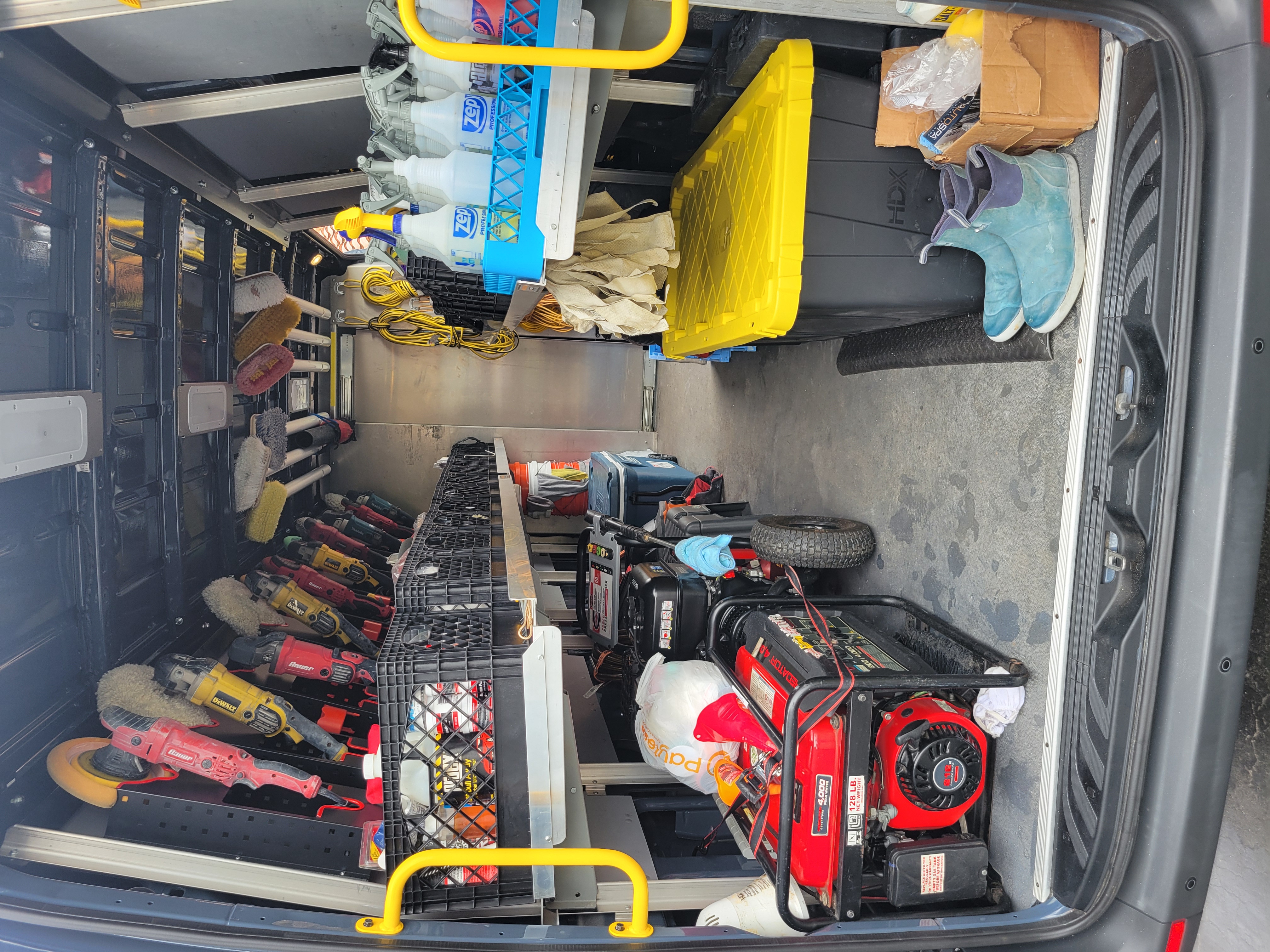 Interior view of fully stocked mobile detailing van showing generator, pressure washer, professional polishers and buffers, brushes, Zep chemicals, and all equipment organized and ready for work.