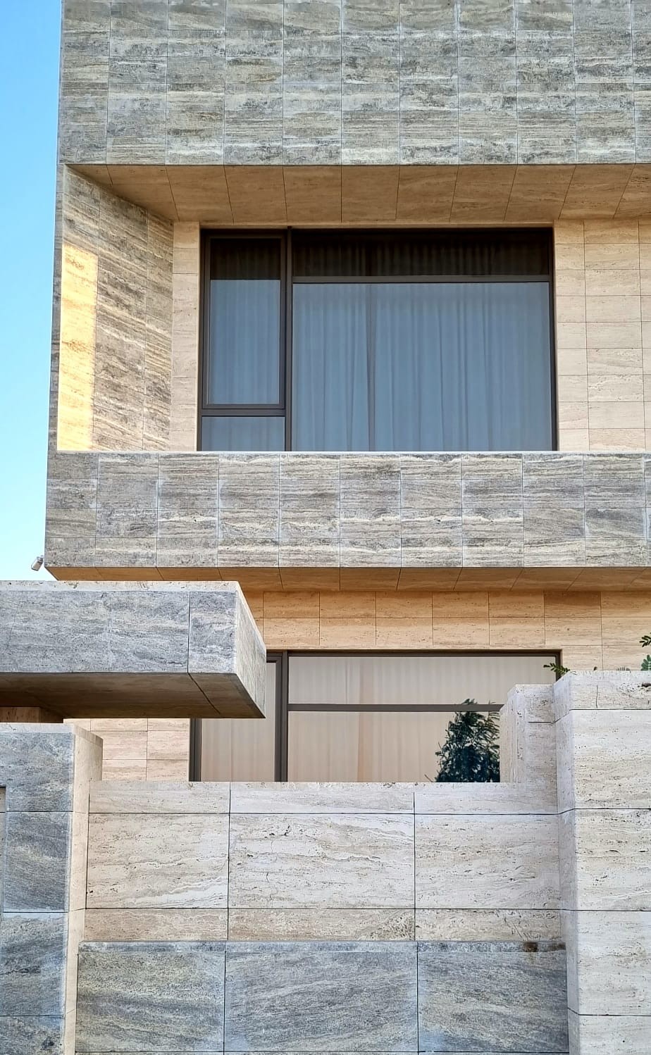 Close-up of beige travertine facade showing window detailing