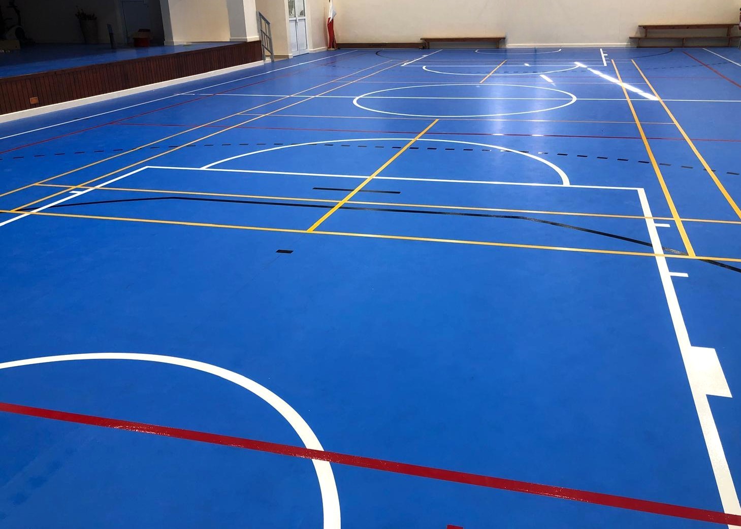 Completed blue PU sports court with professional line markings at Budaiya School