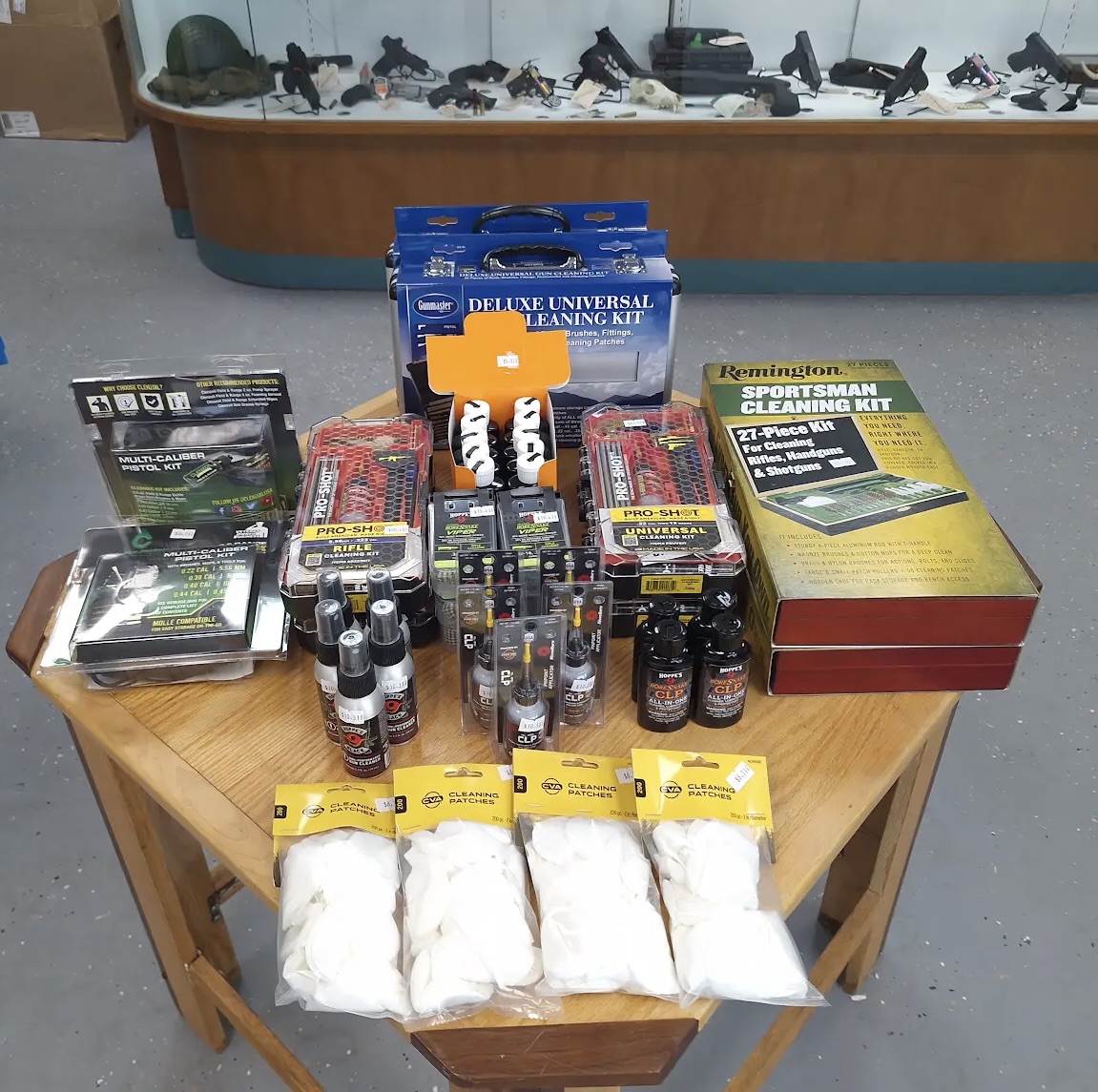 Firearm cleaning kits, oils, patches, and maintenance accessories displayed on a wooden table inside Freedom Forever Firearms in Manistique, Michigan.