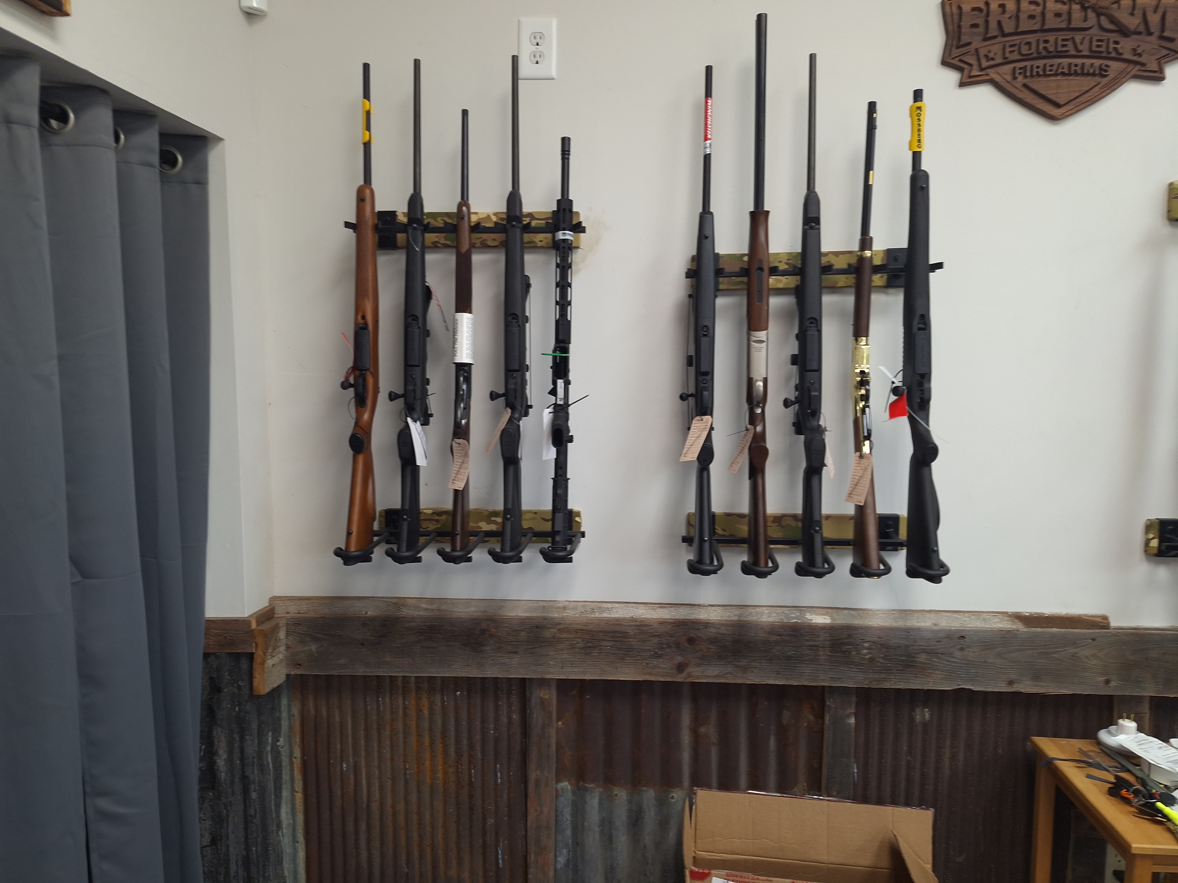 Long firearms displayed vertically on a wall rack inside Freedom Forever Firearms in Manistique, Michigan.