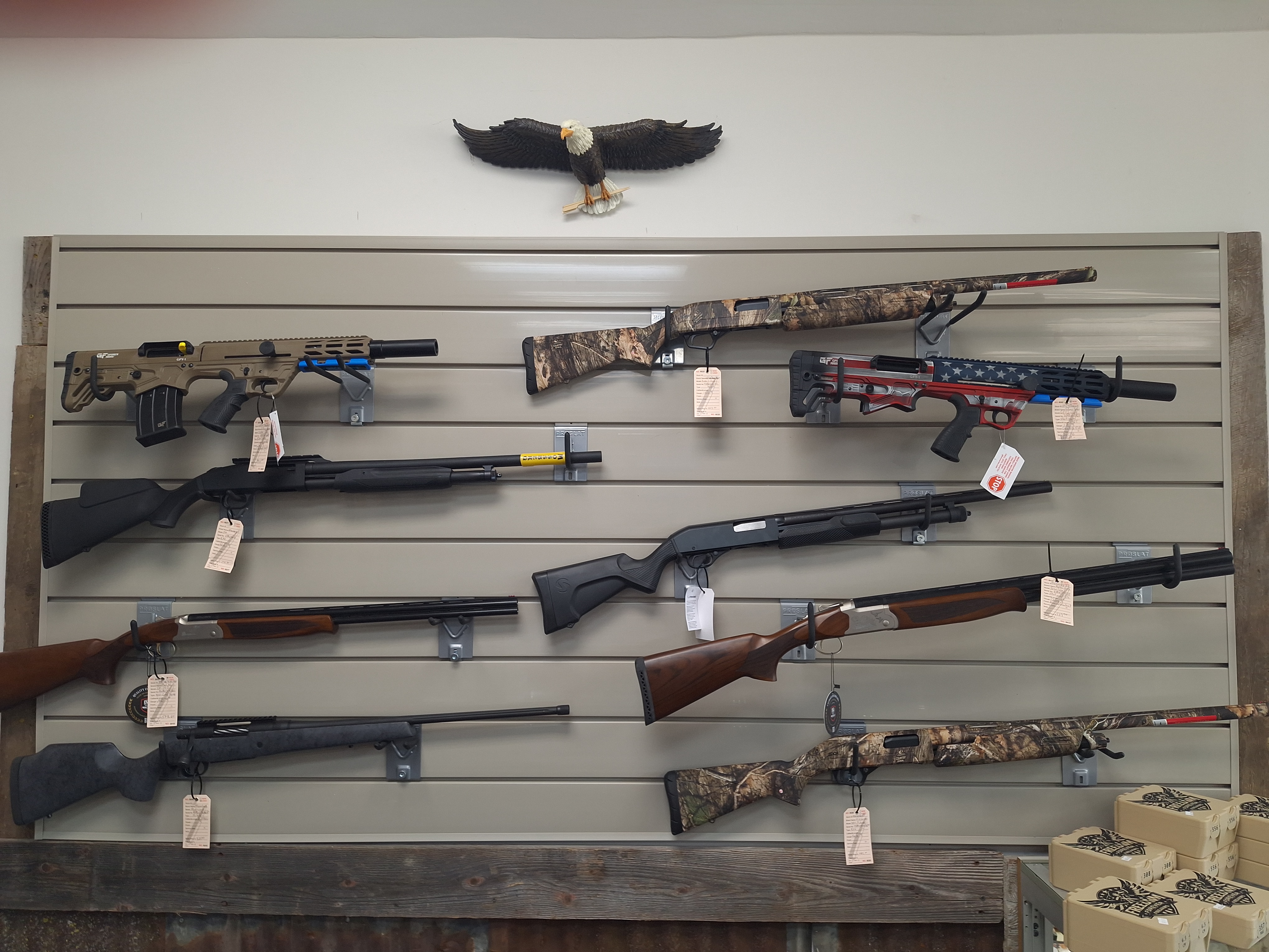 Multiple long firearms displayed horizontally on a wall inside Freedom Forever Firearms in Manistique, Michigan.