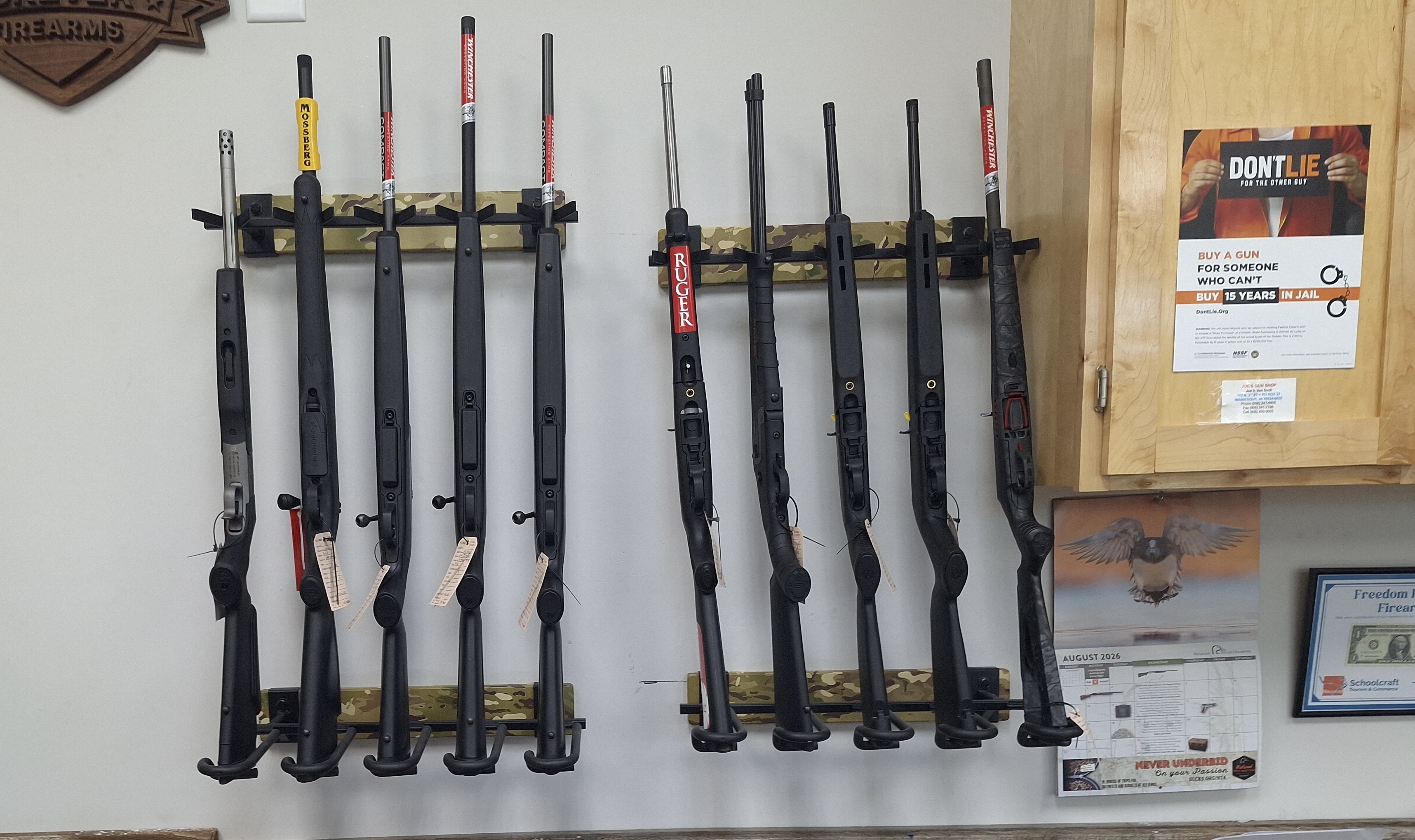 Multiple long firearms displayed vertically on wall-mounted racks inside Freedom Forever Firearms in Manistique, Michigan.