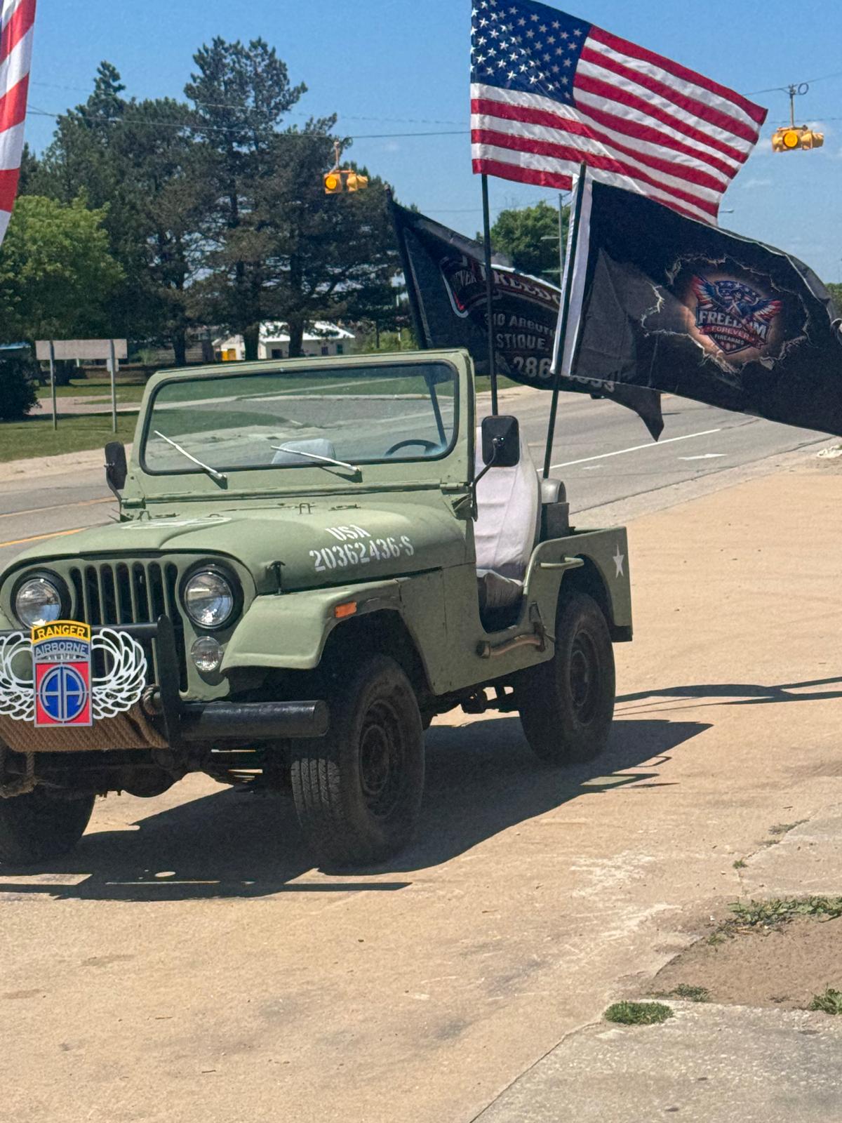 Military-style Jeep with the American flag and Freedom Forever Firearms branded flag in Manistique, Michigan.