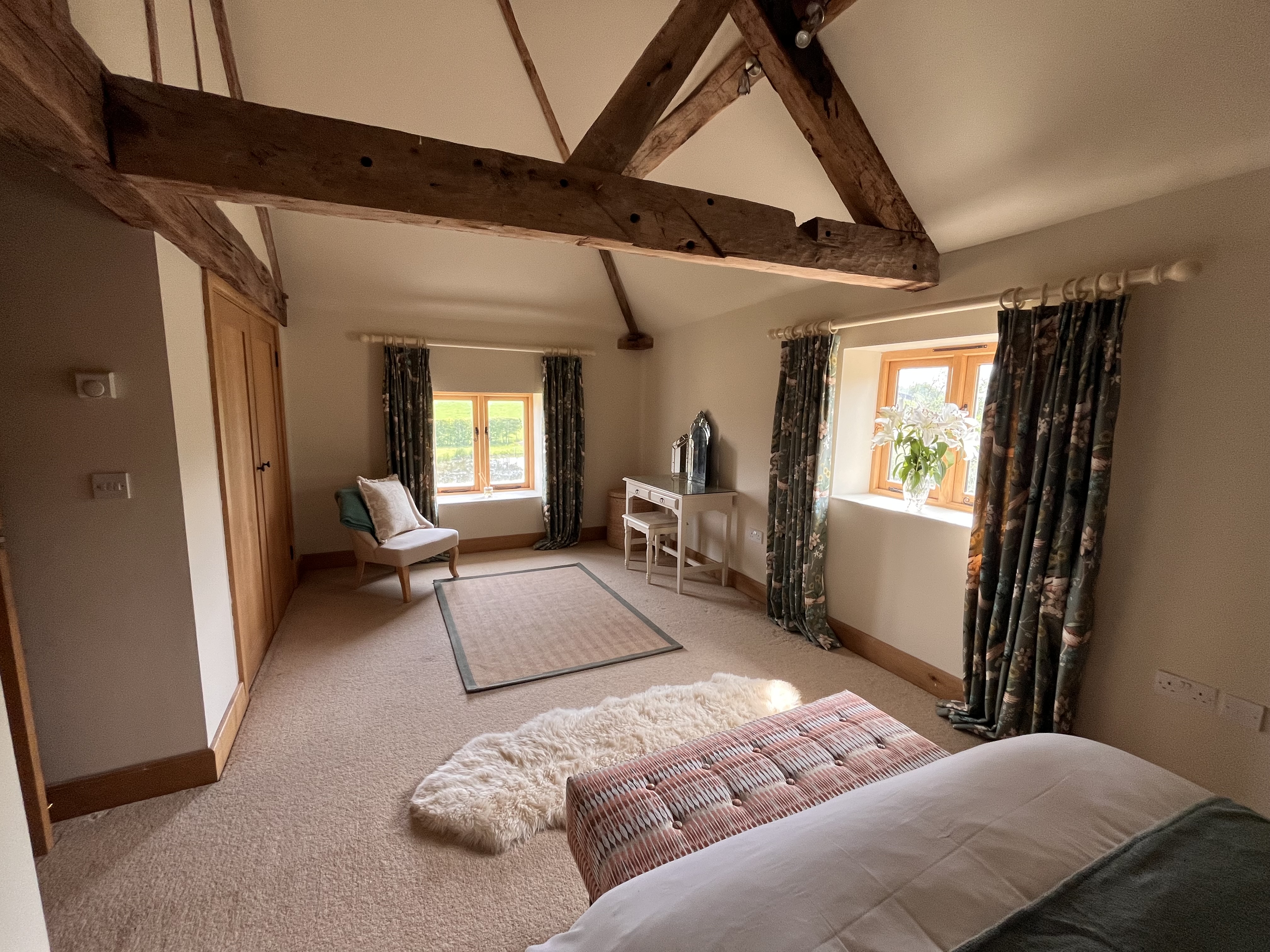 The Pond Room spacious bedroom with rustic beamed ceilings, vanity table, and countryside window