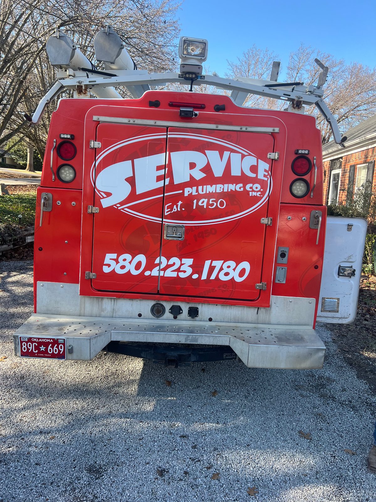 Service Plumbing red service truck rear view - 580.223.1780 Est. 1950