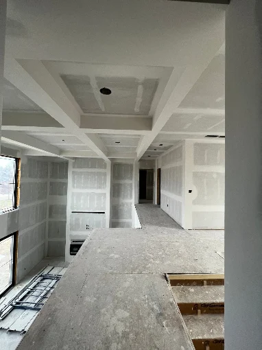 New construction drywall installation with coffered ceiling framing