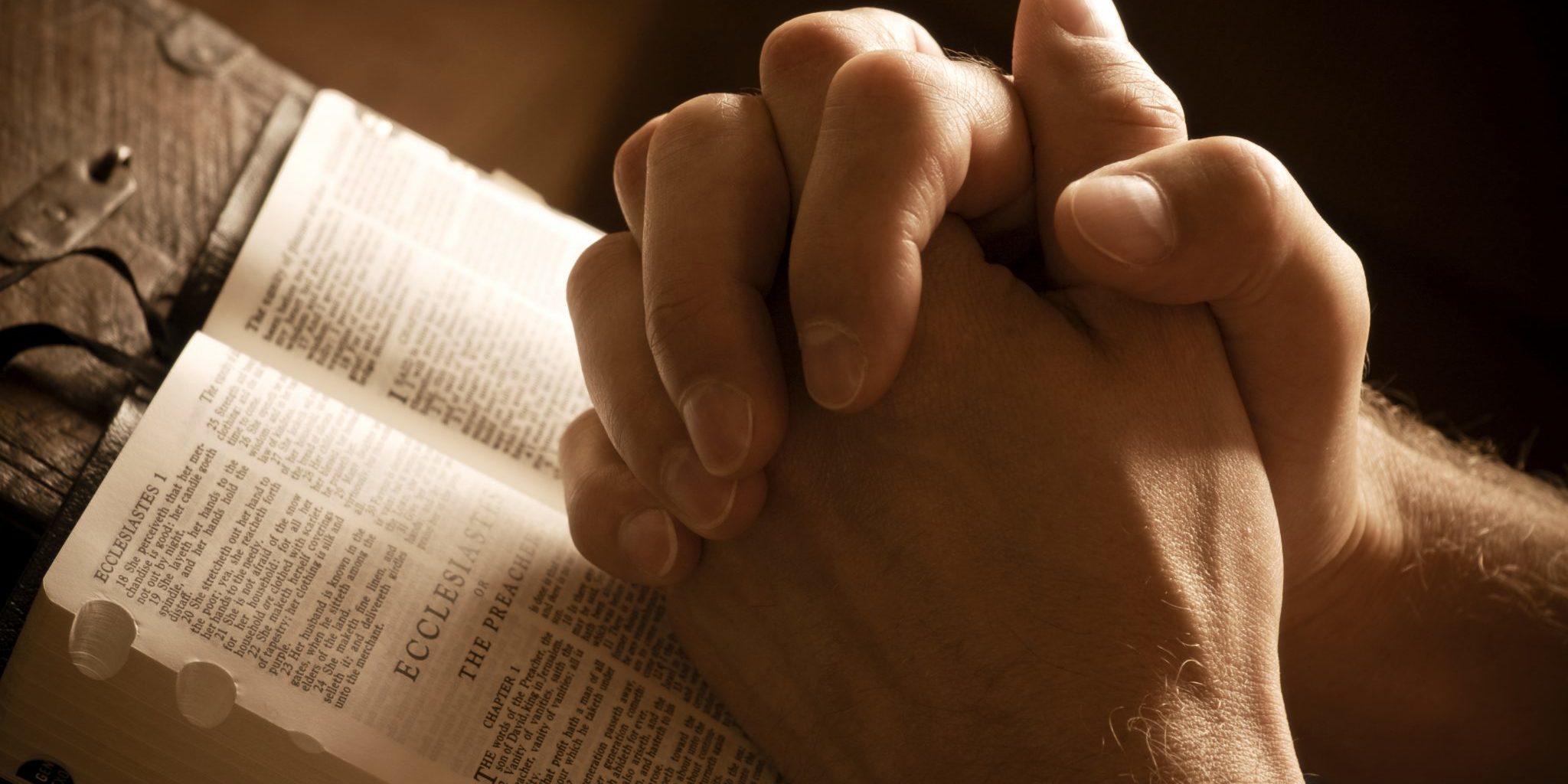Praying hands on open bible