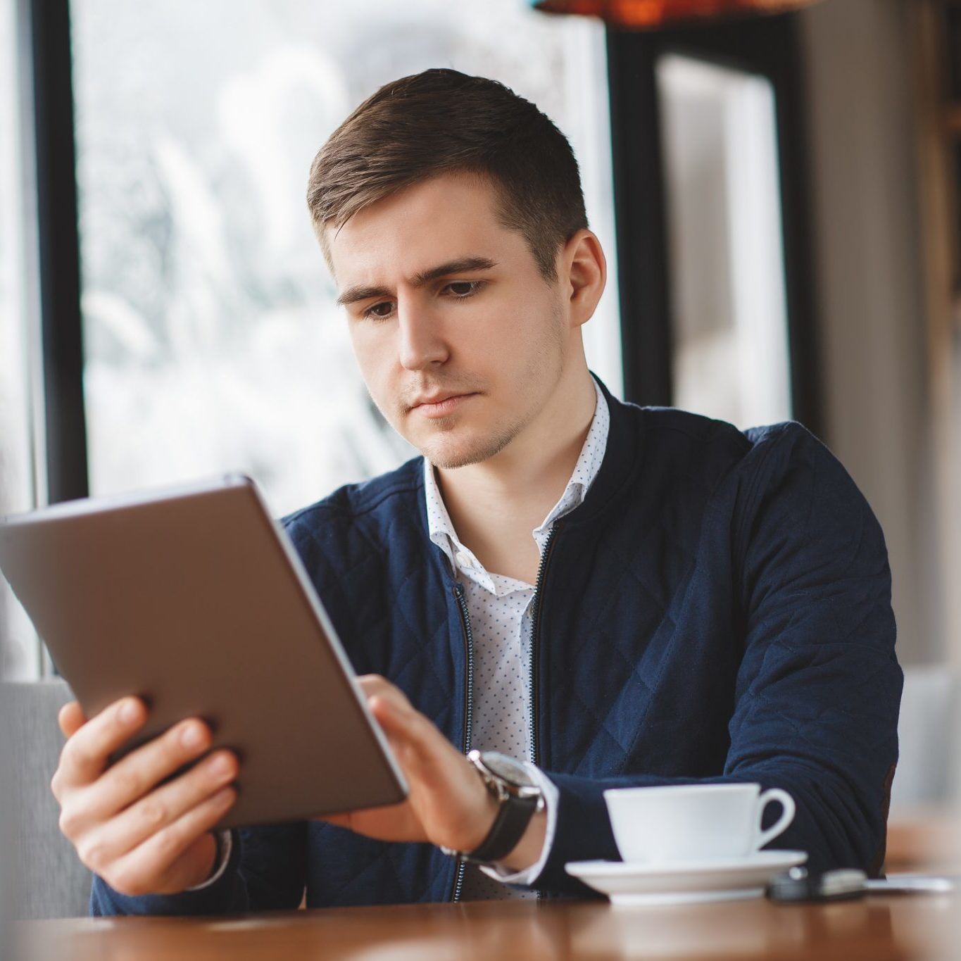 Man drinking coffee with tablet