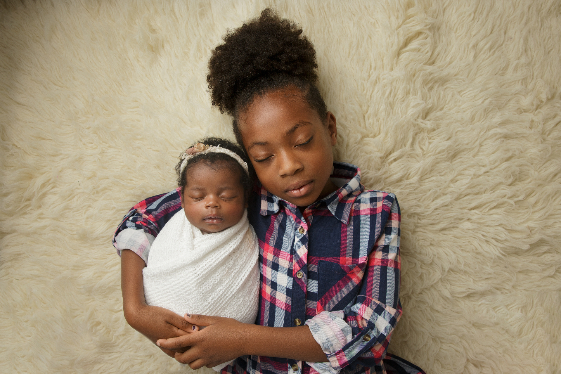Big sister cradling her swaddled newborn sibling