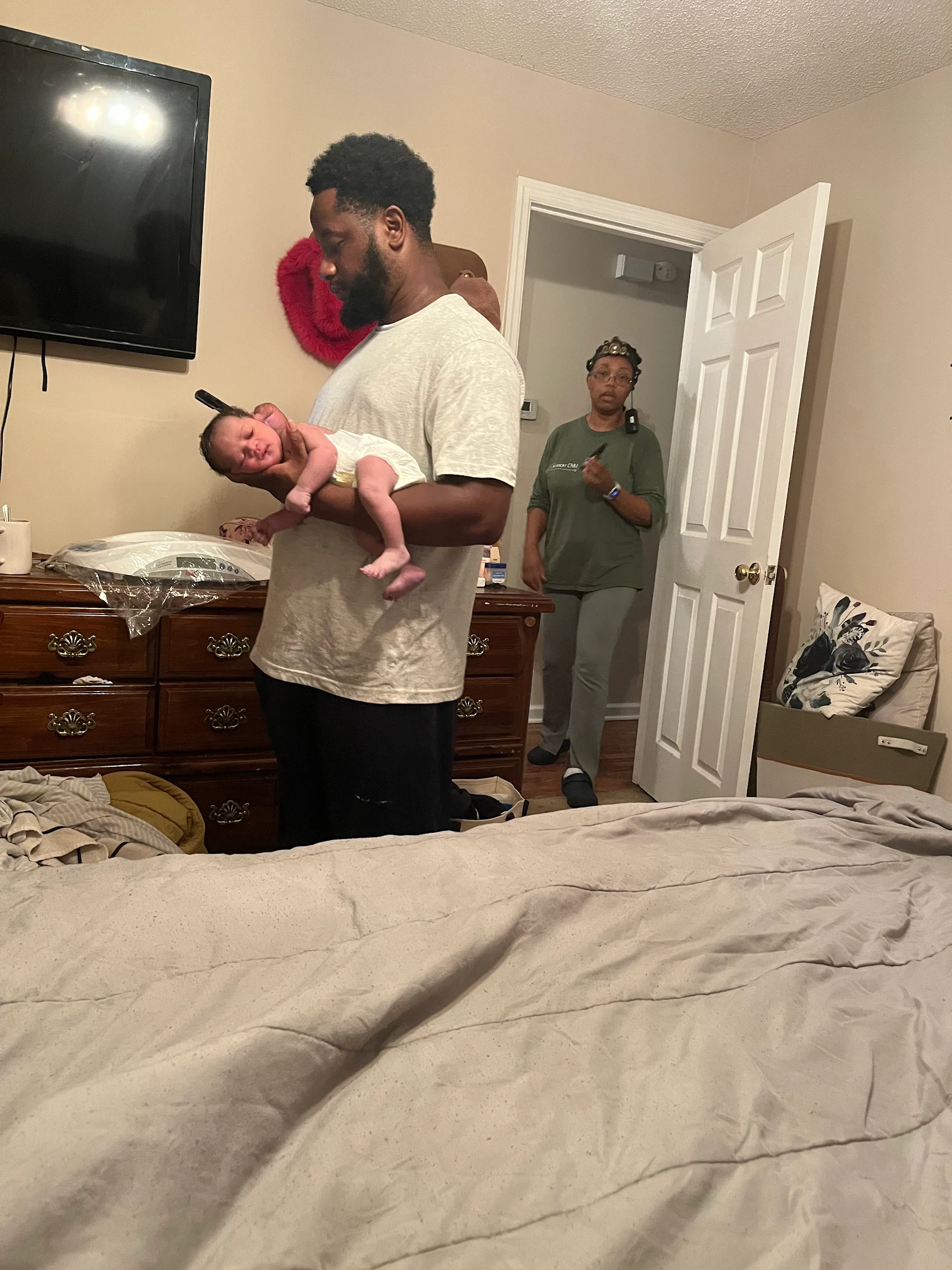 Father holding his newborn at home with midwife support nearby