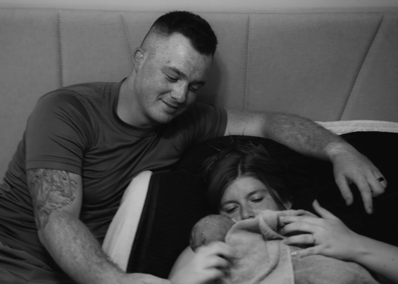 Parents cradling their newborn together at home