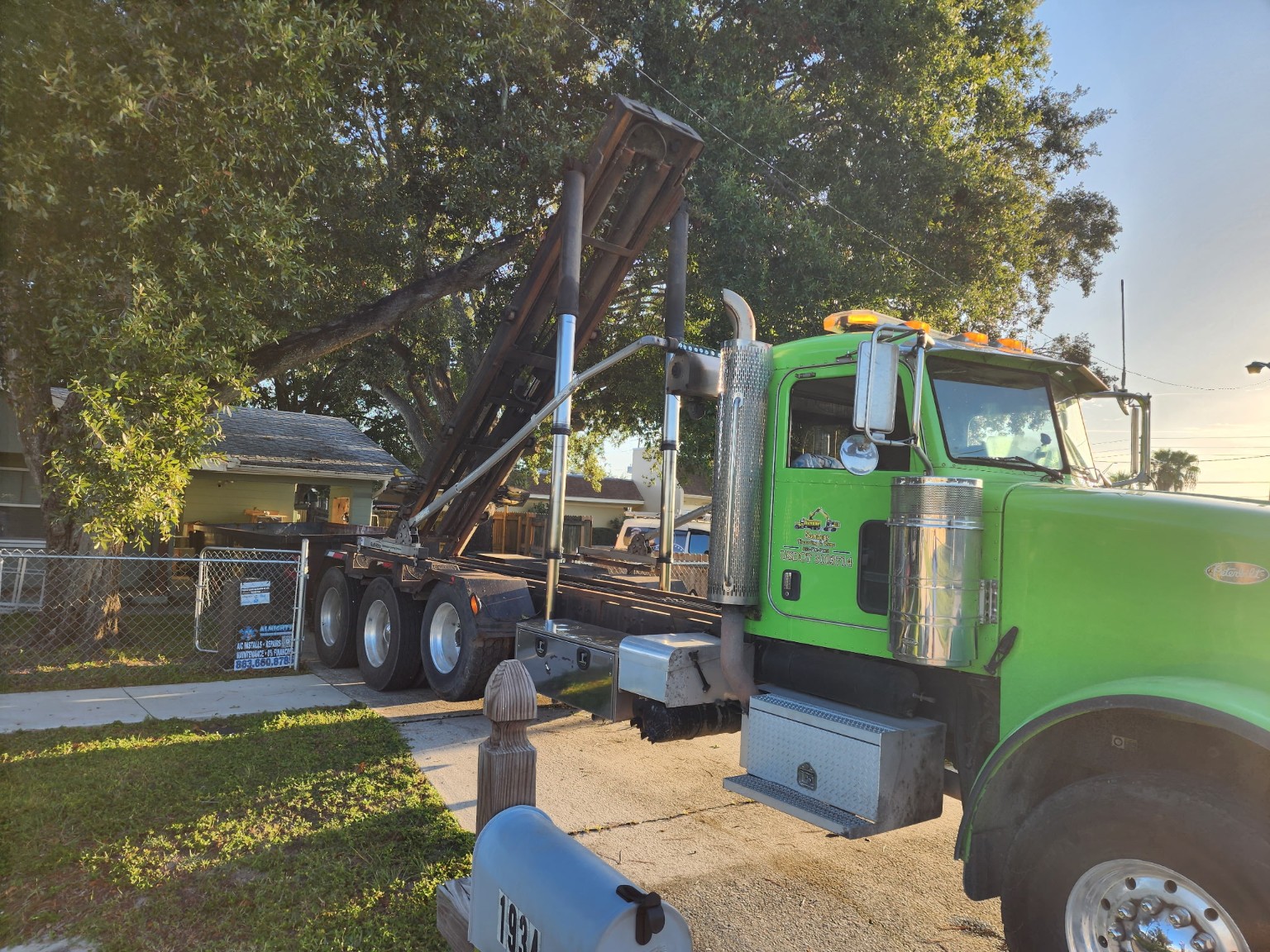 Green Peterbilt roll-off truck used for dumpster rental deliveries throughout Lakeland and Central Florida