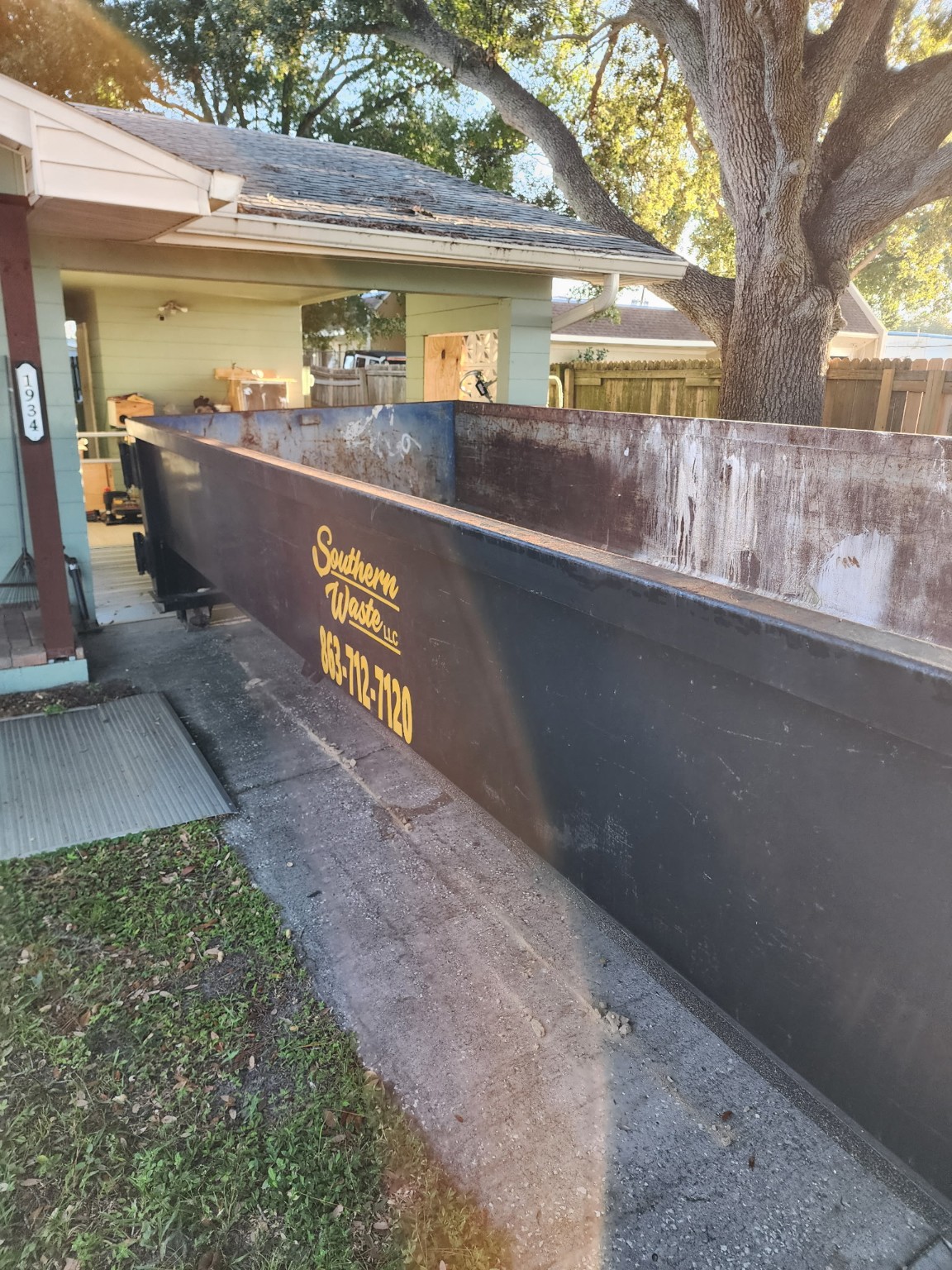 Close-up view of a black roll-off dumpster bin positioned at a residential property for debris removal