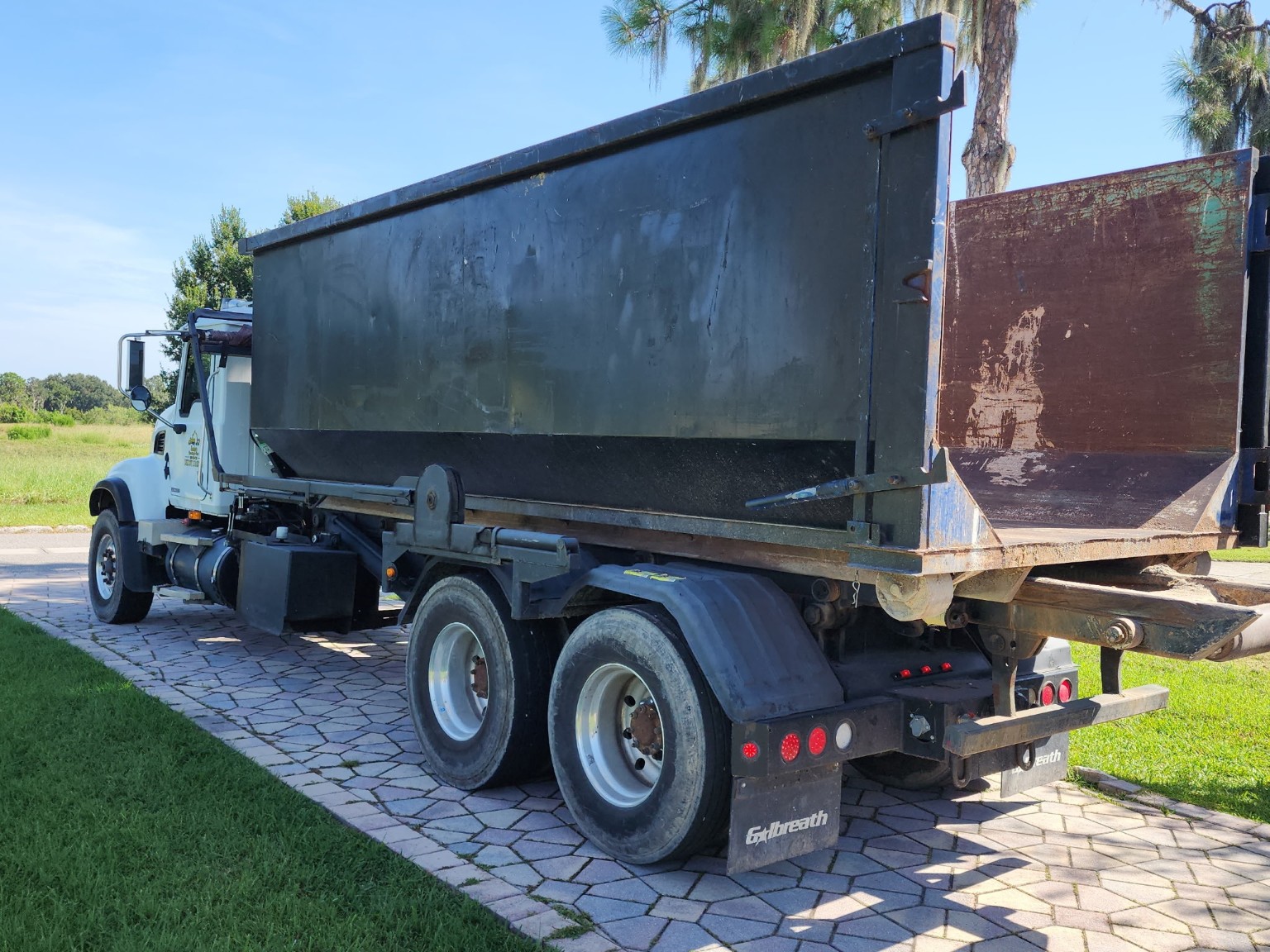 White roll-off delivery truck with empty dumpster container ready for rental delivery in Central Florida