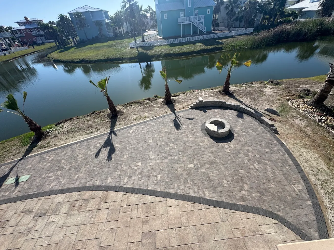 Finished waterfront paver patio with fire pit by Riverstone Landscaping