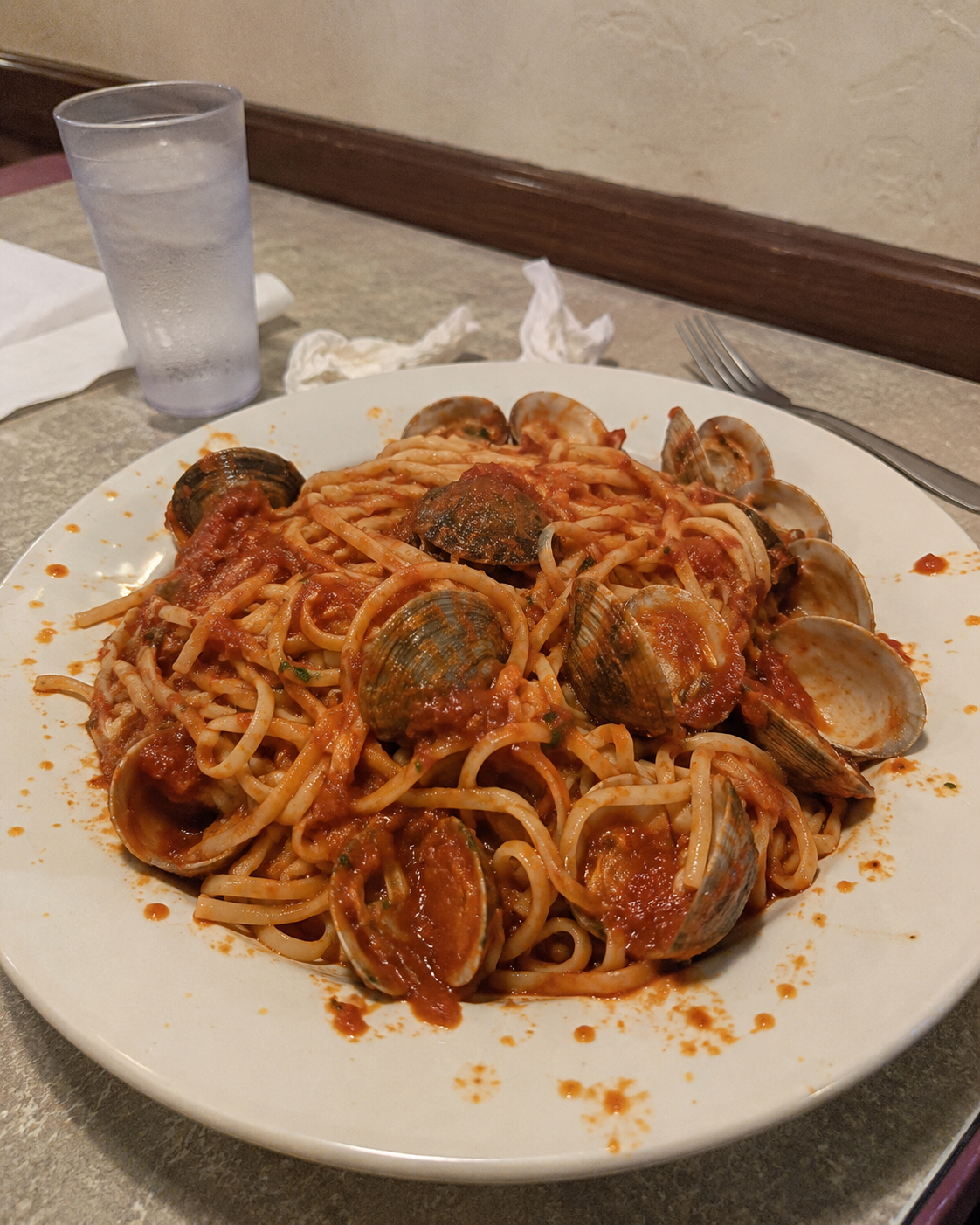Before AI content optimization - casual spaghetti alle vongole on white plate with informal plating and basic restaurant lighting