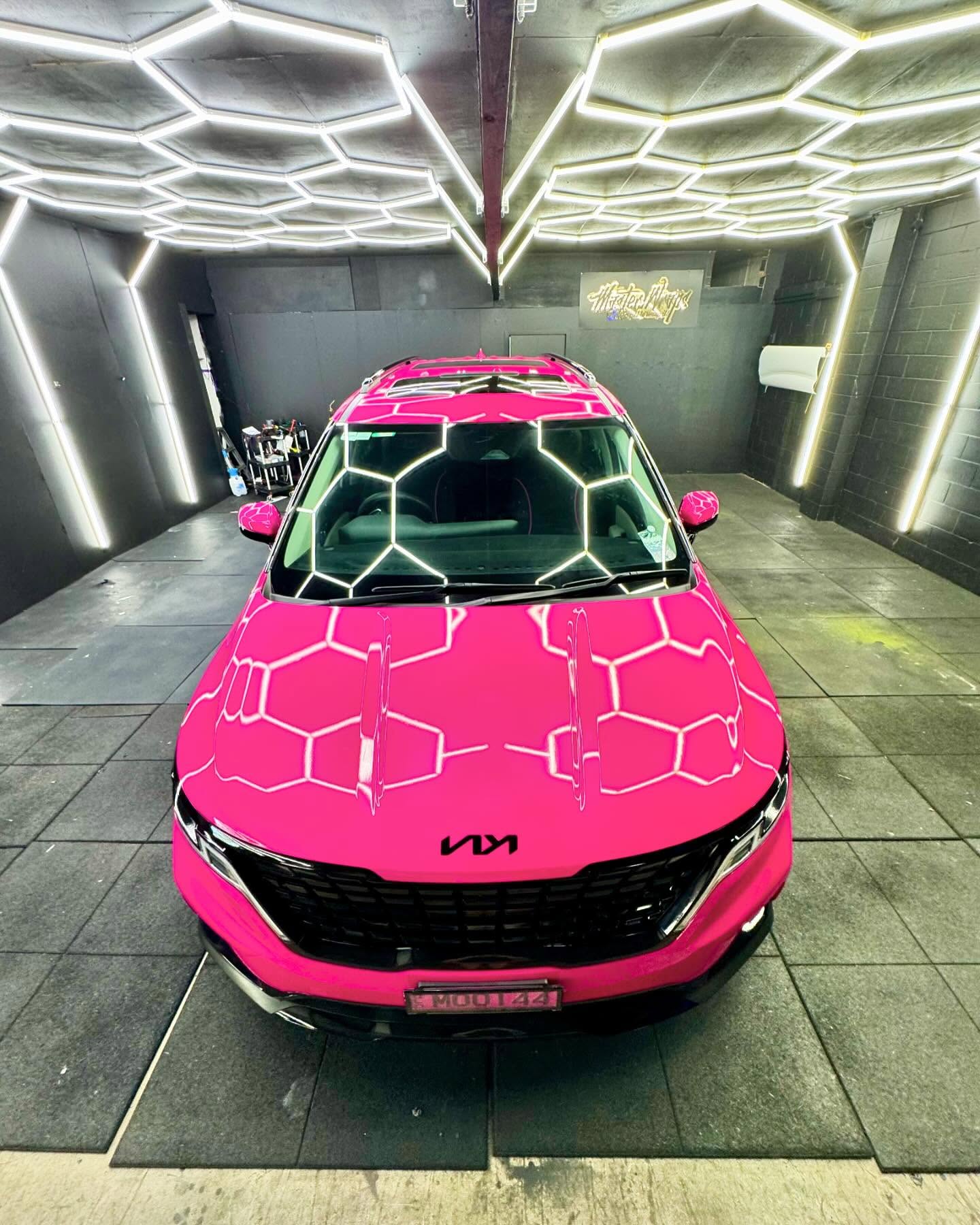 Bright pink wrapped Kia Carnival front view in the Master Wraps studio