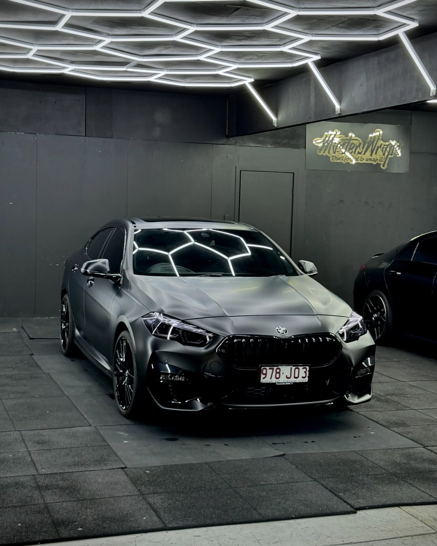 Satin dark grey BMW sedan with blackout package inside the Master Wraps studio