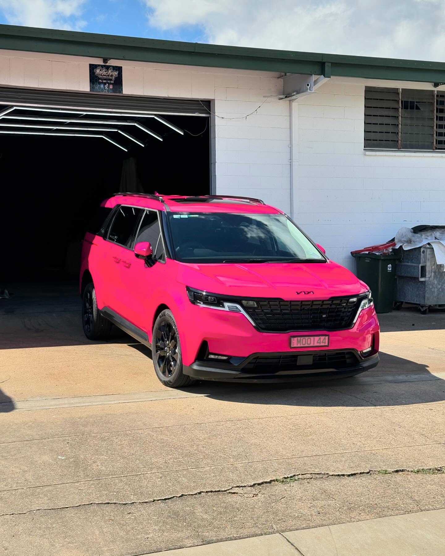 Bright pink wrapped Kia Carnival front quarter view outside