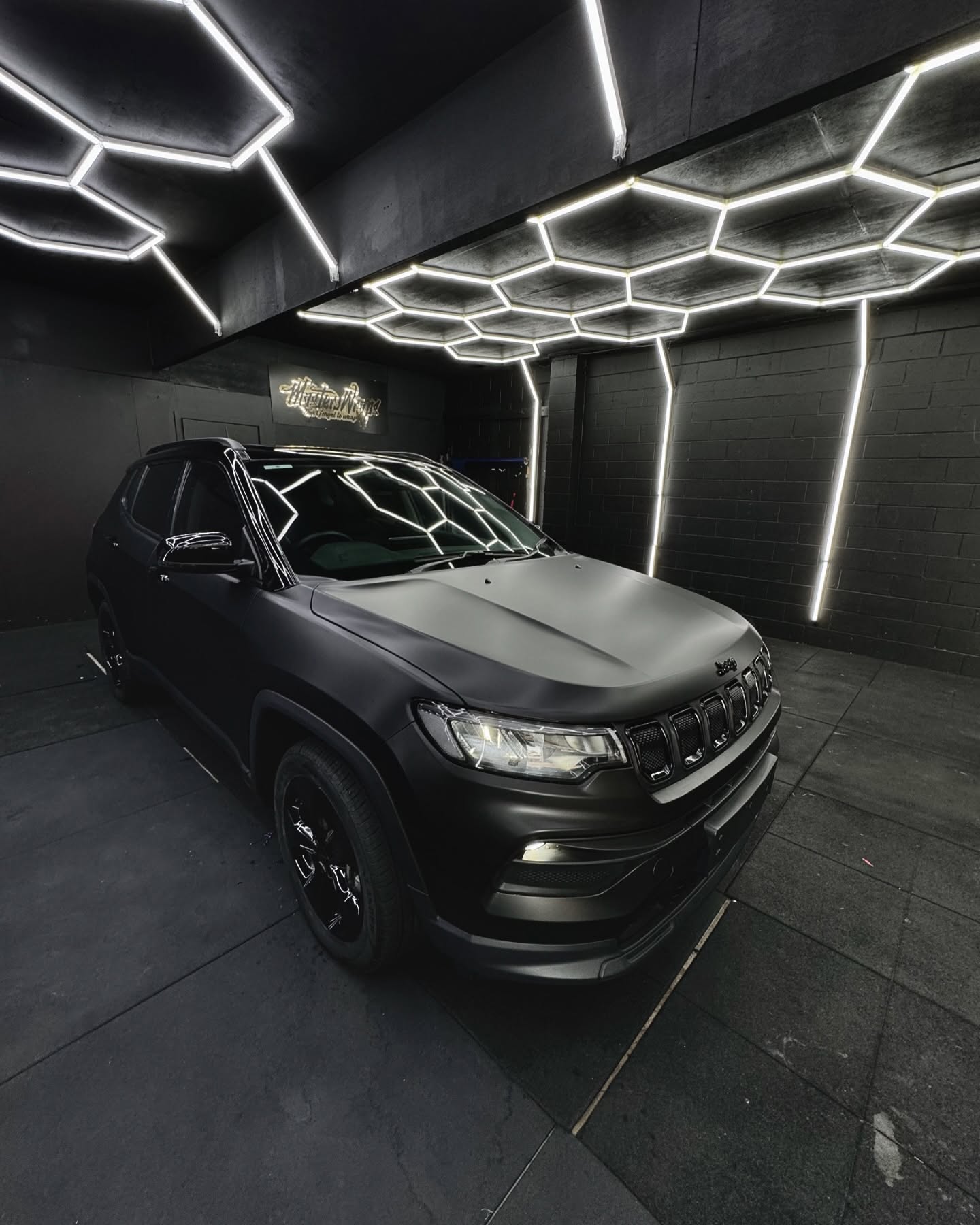 Matte black Jeep SUV front quarter view inside the Master Wraps studio