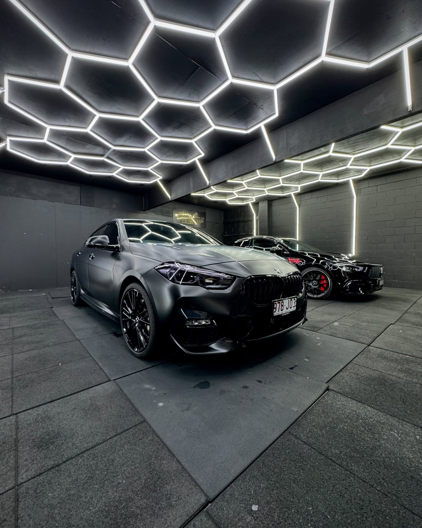 Matte black BMW sedan front view inside the Master Wraps studio