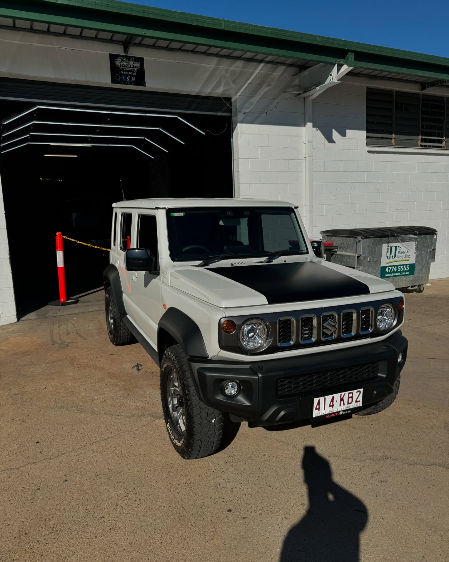 White Suzuki Jimny 5-door with black hood wrap parked outside Master Wraps