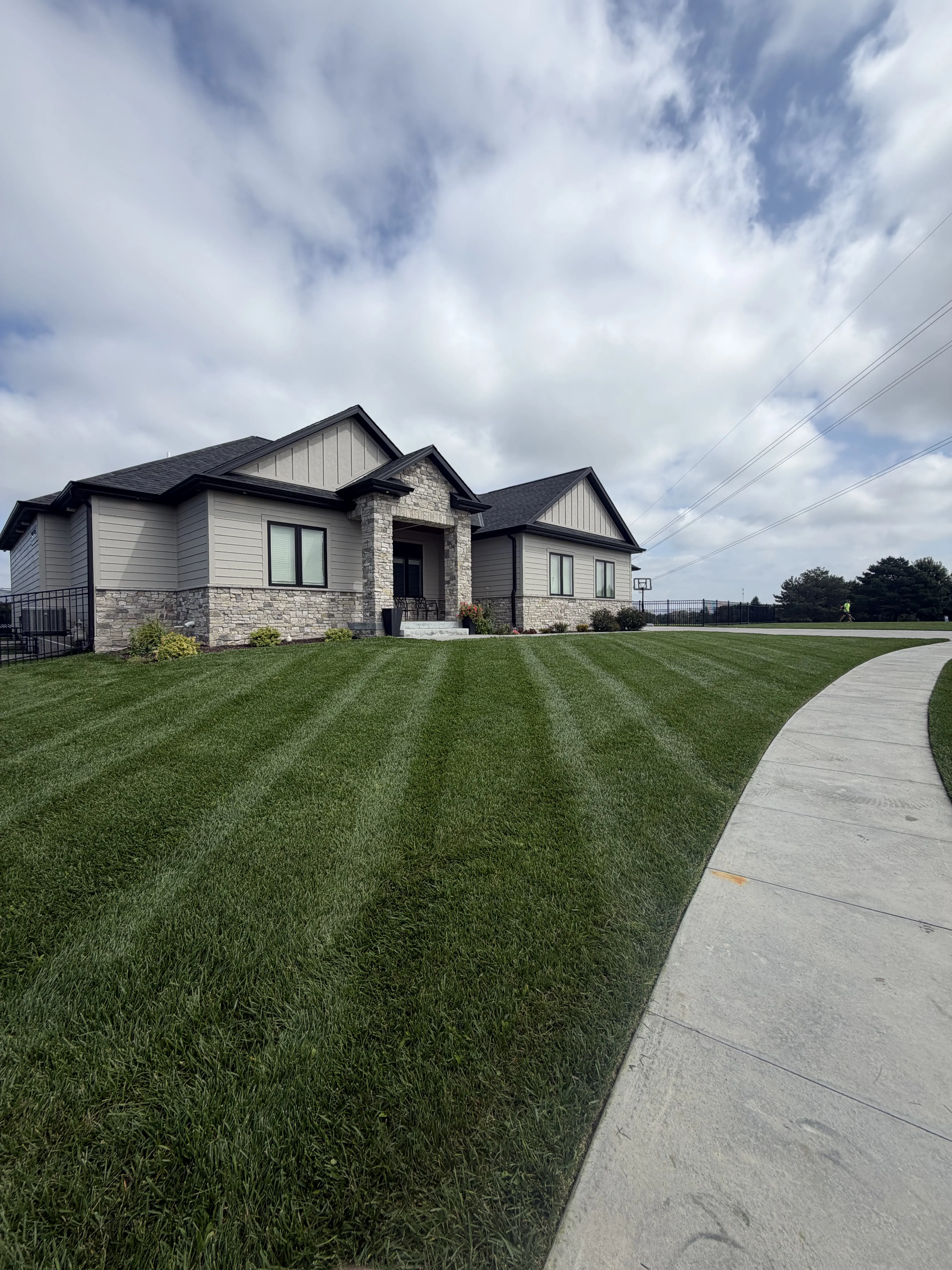 Beautifully striped front lawn with curved walkway and stone home in Lincoln, NE
