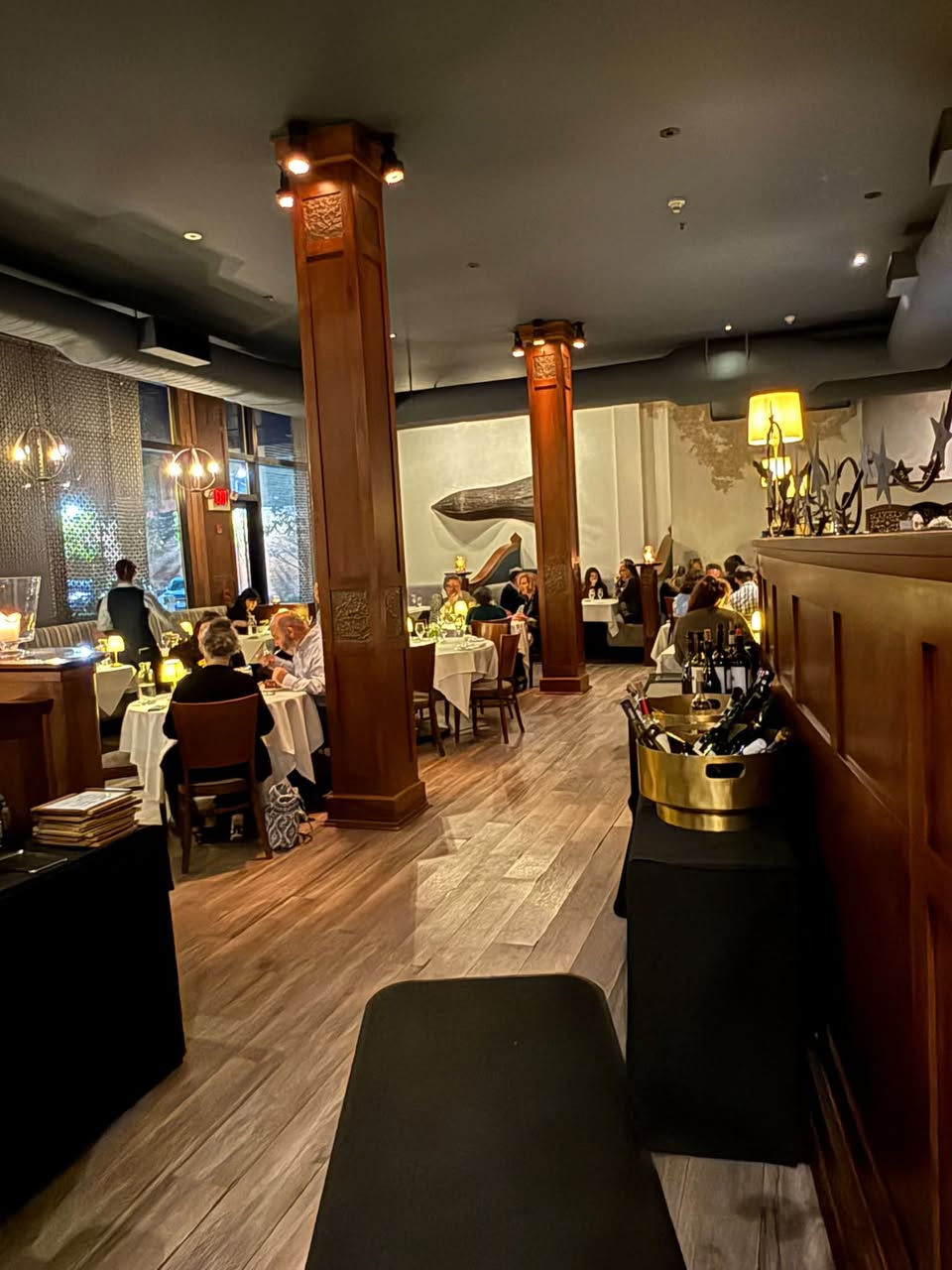 Gracie's softly illuminated dining room with white tablecloths and warm wooden columns