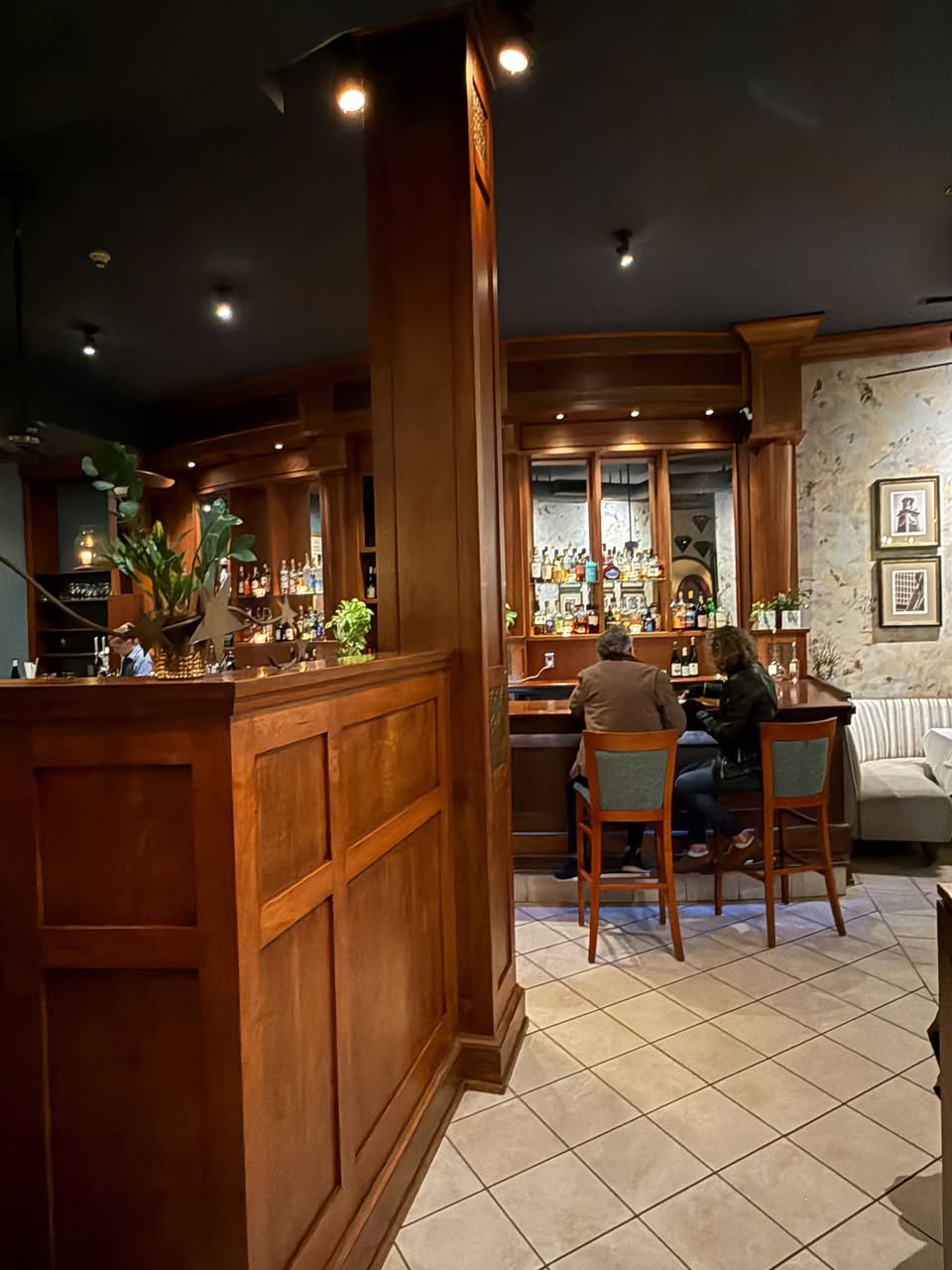 The intimate wooden bar at Gracie's with patrons enjoying evening cocktails