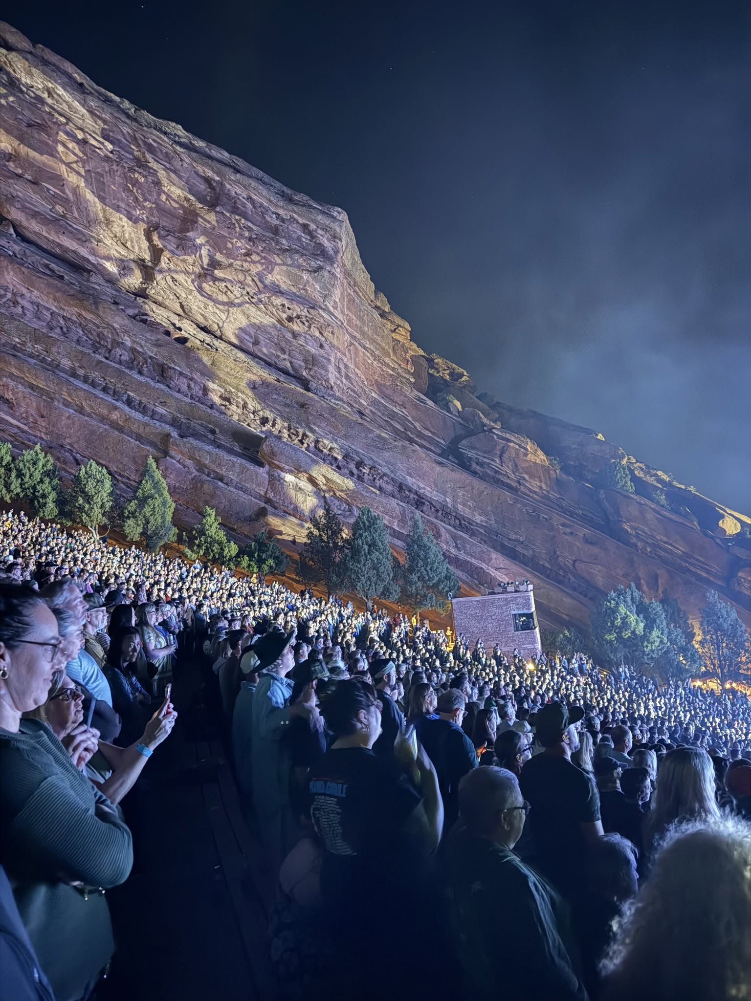 Packed amphitheater crowd stretching up the mountain alongside the rock face