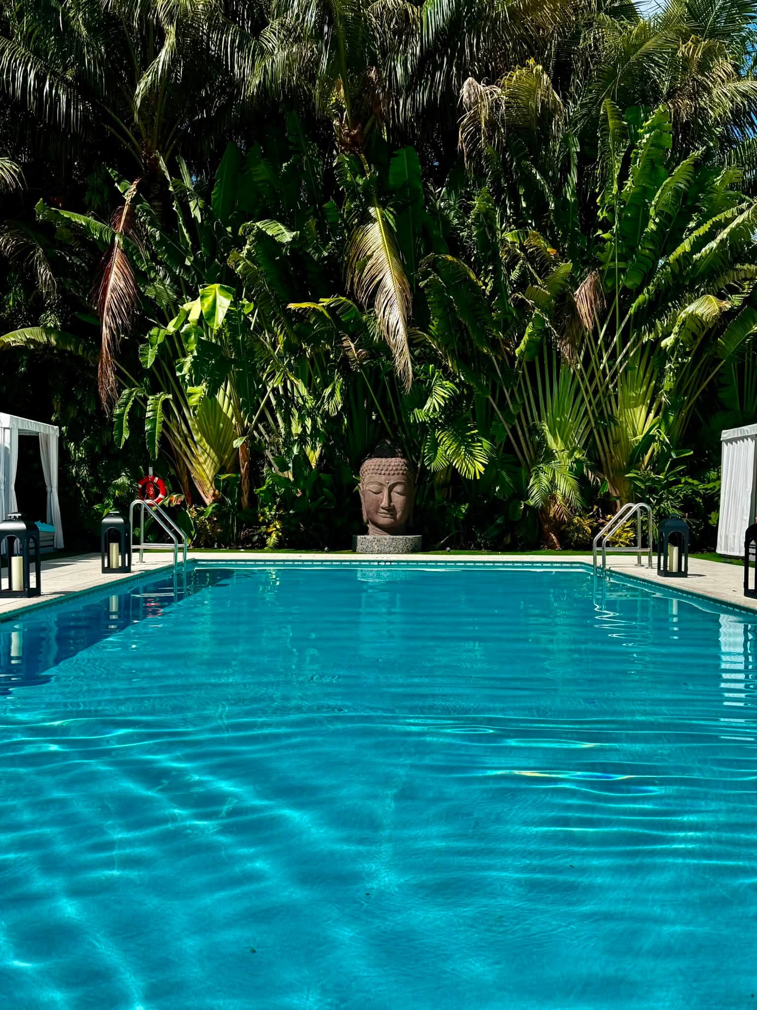 The Zen Pool at Bungalows Key Largo - tranquil turquoise pool with Buddha statue surrounded by lush tropical palms