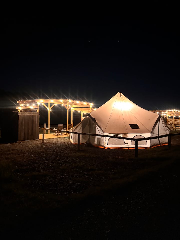 Exterior view of illuminated glamping tent at night at Faith Farm