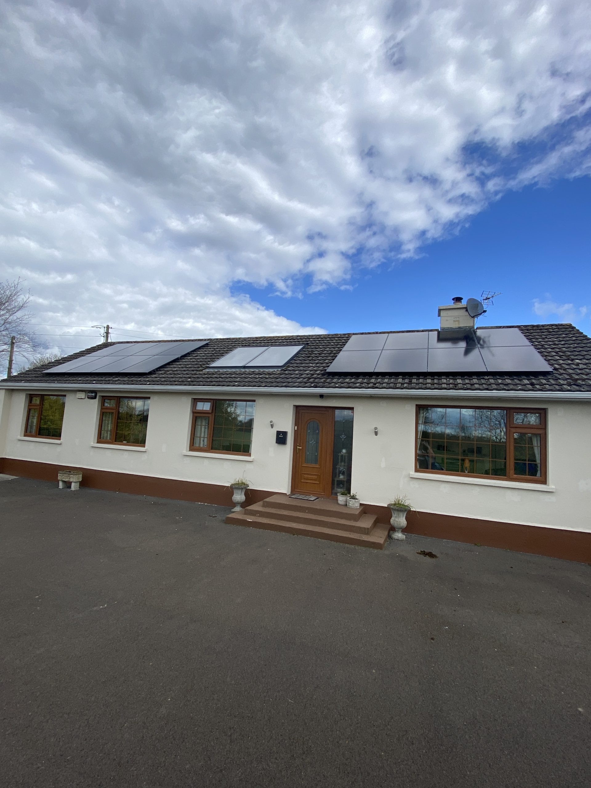 Irish bungalow with large solar PV array on roof under bright blue sky