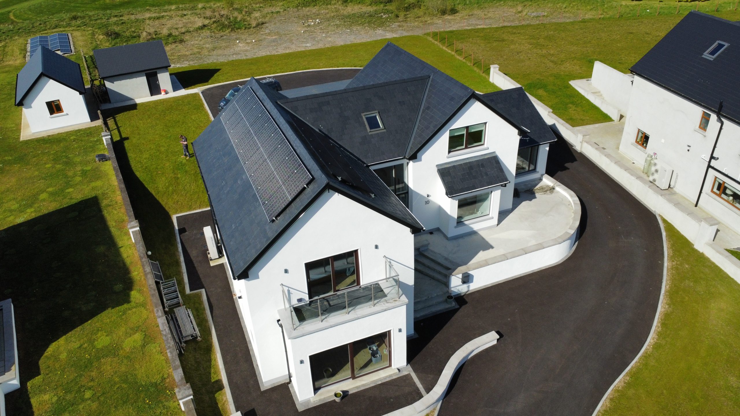 Aerial drone shot of modern white Irish home with full solar PV array installed on roof