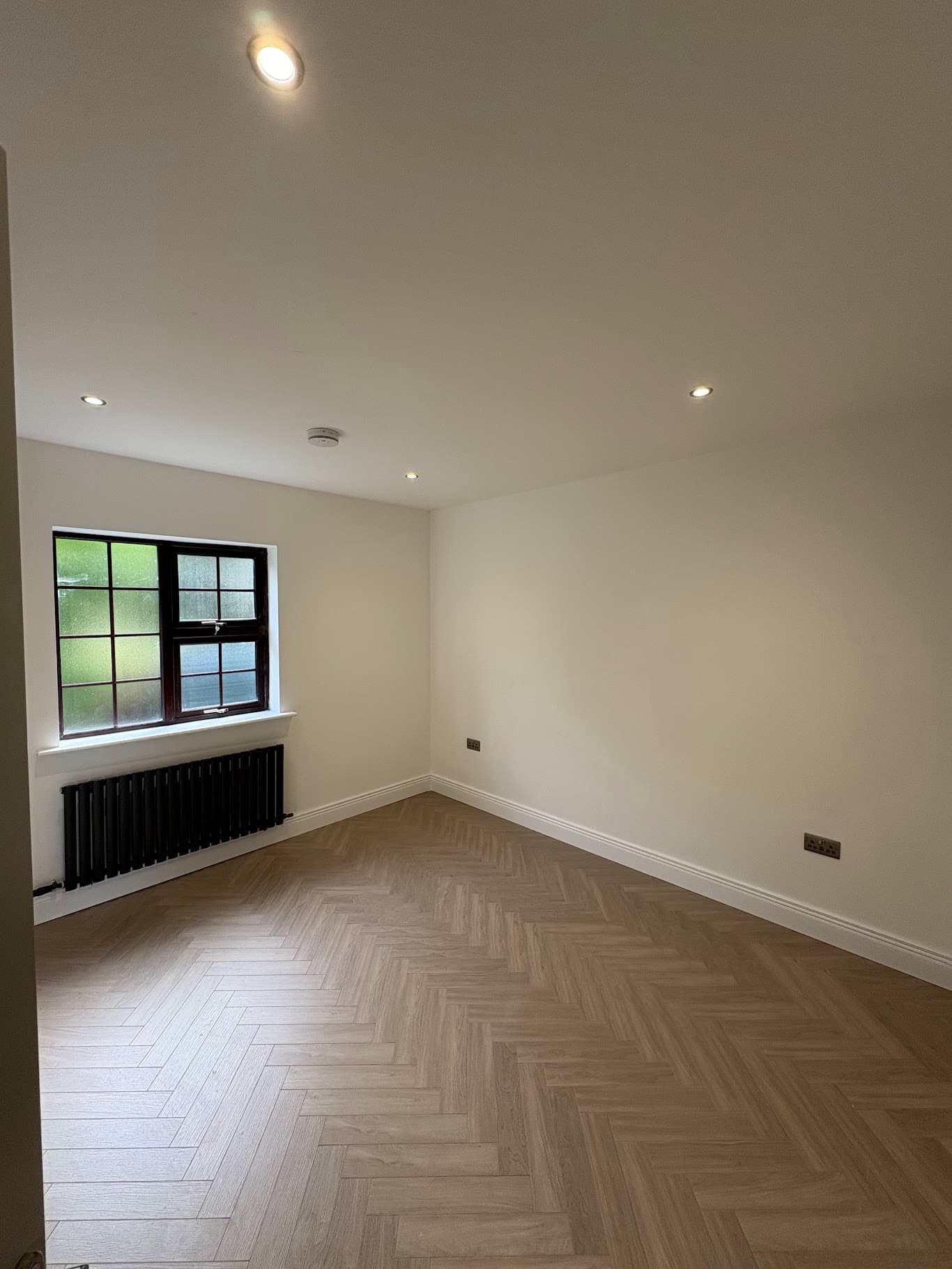 Clean and modern domestic room interior with recessed LED downlights and herringbone flooring