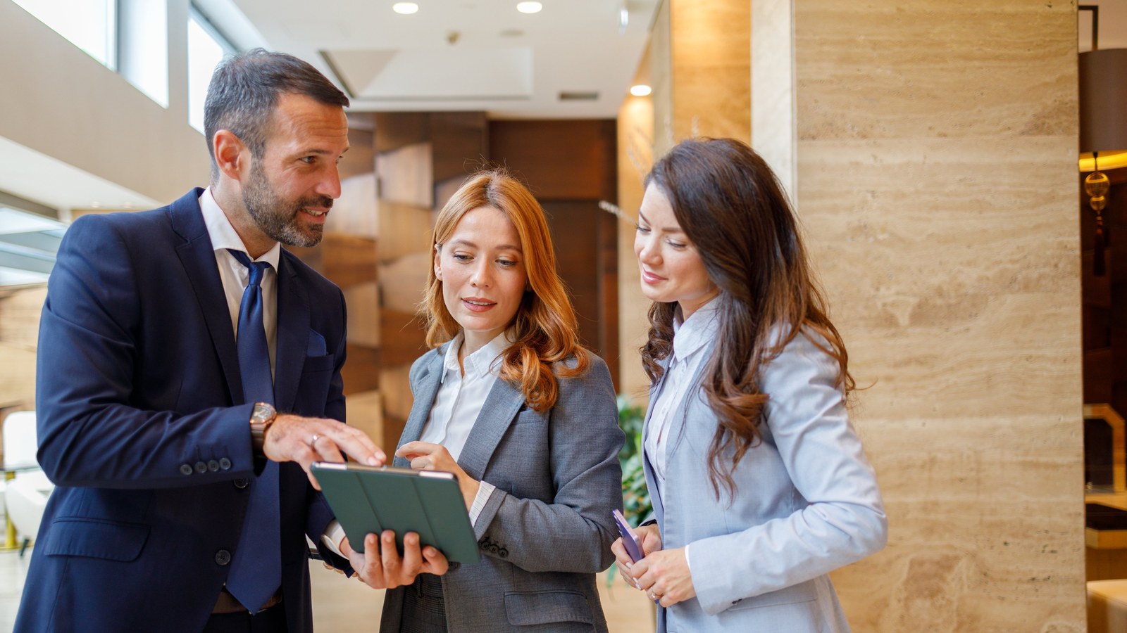 Insurance agents and clients reviewing policy information on a tablet.
