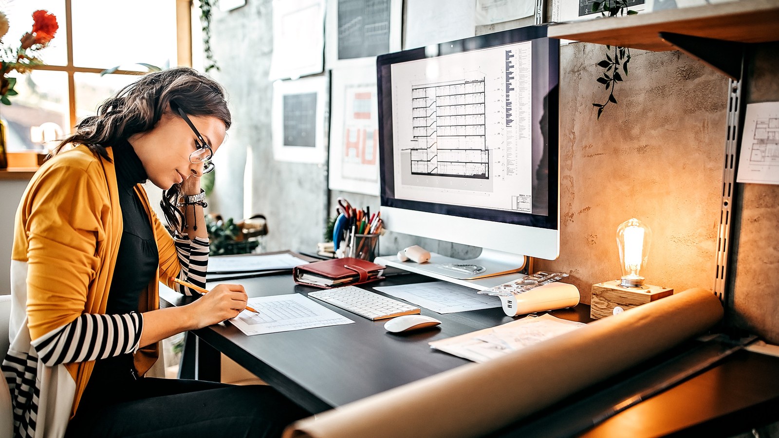 An architect reviewing drawings on dual monitors in a modern design studio.