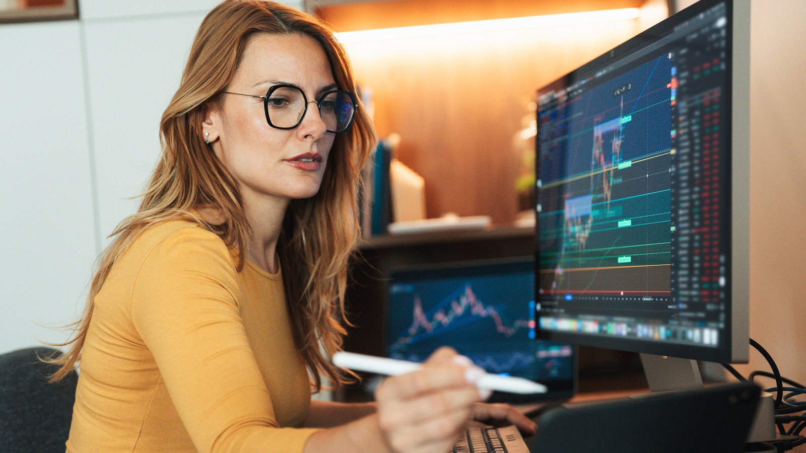Financial advisor analyzing market charts on computer screen.